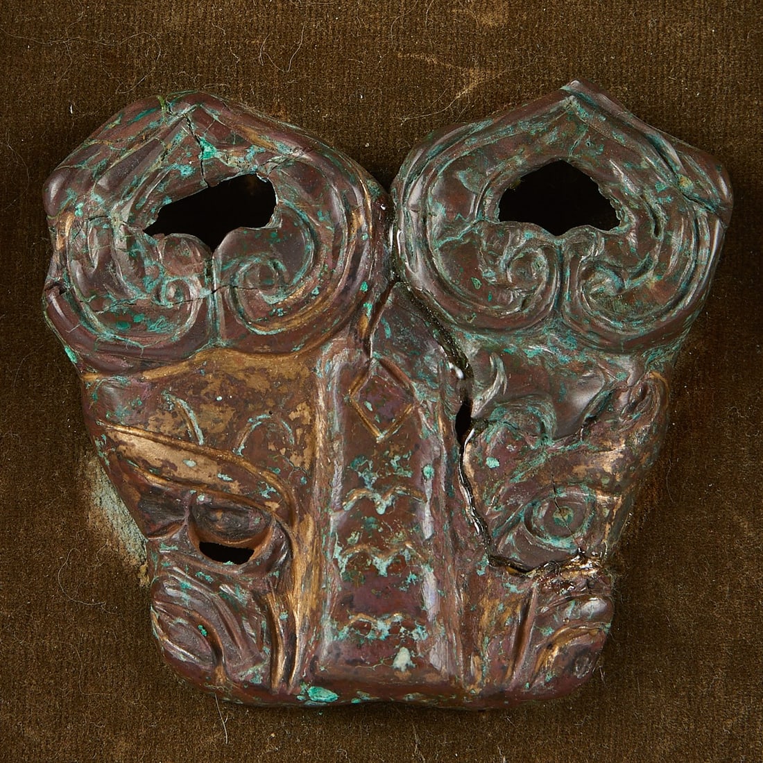 Chinese Bronze Taotie Mask - Repaired: Archaic Chinese bronze cast in the form of a "taotie" mask. This example with downward curling horns, low-relief cast facial features, and a brown patina with areas of verdigris.(Mask) Height: 3 in x