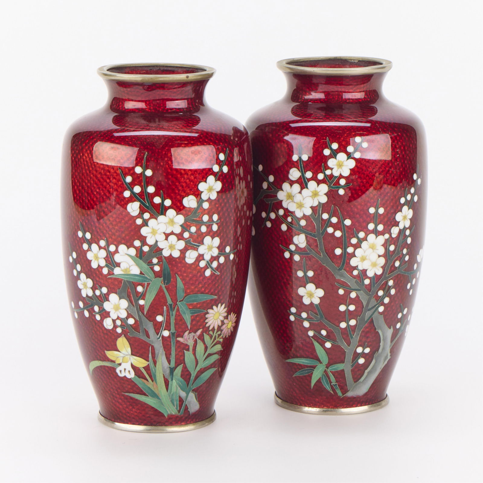 Pair Japanese Sato Pigeon Blood Cloisonne Vases: Pair of Chinese pigeon blood cloisonne vases. Decorated with cherry blossoms or prunus blossoms. Stamped "Japan Sato" along the metal footrims.(Each) Height: 7 1/2 in x diameter: 4 in.