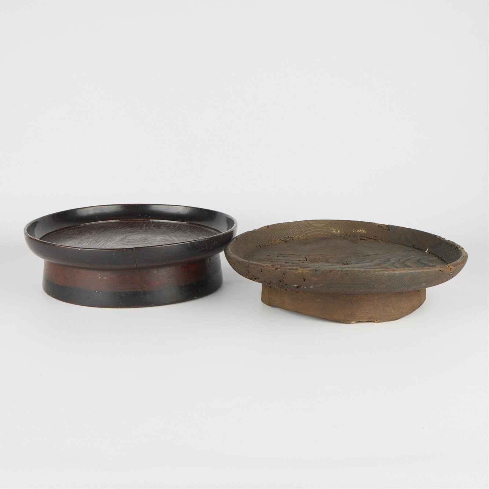 2 Japanese Wooden Pedestal Platters: Group of two Japanese wooden footed or pedestal platters. (Smaller) Height: 3 3/4 in x diameter: 14 in. (Larger) Height: 4 in x diameter: 14 1/2 in.