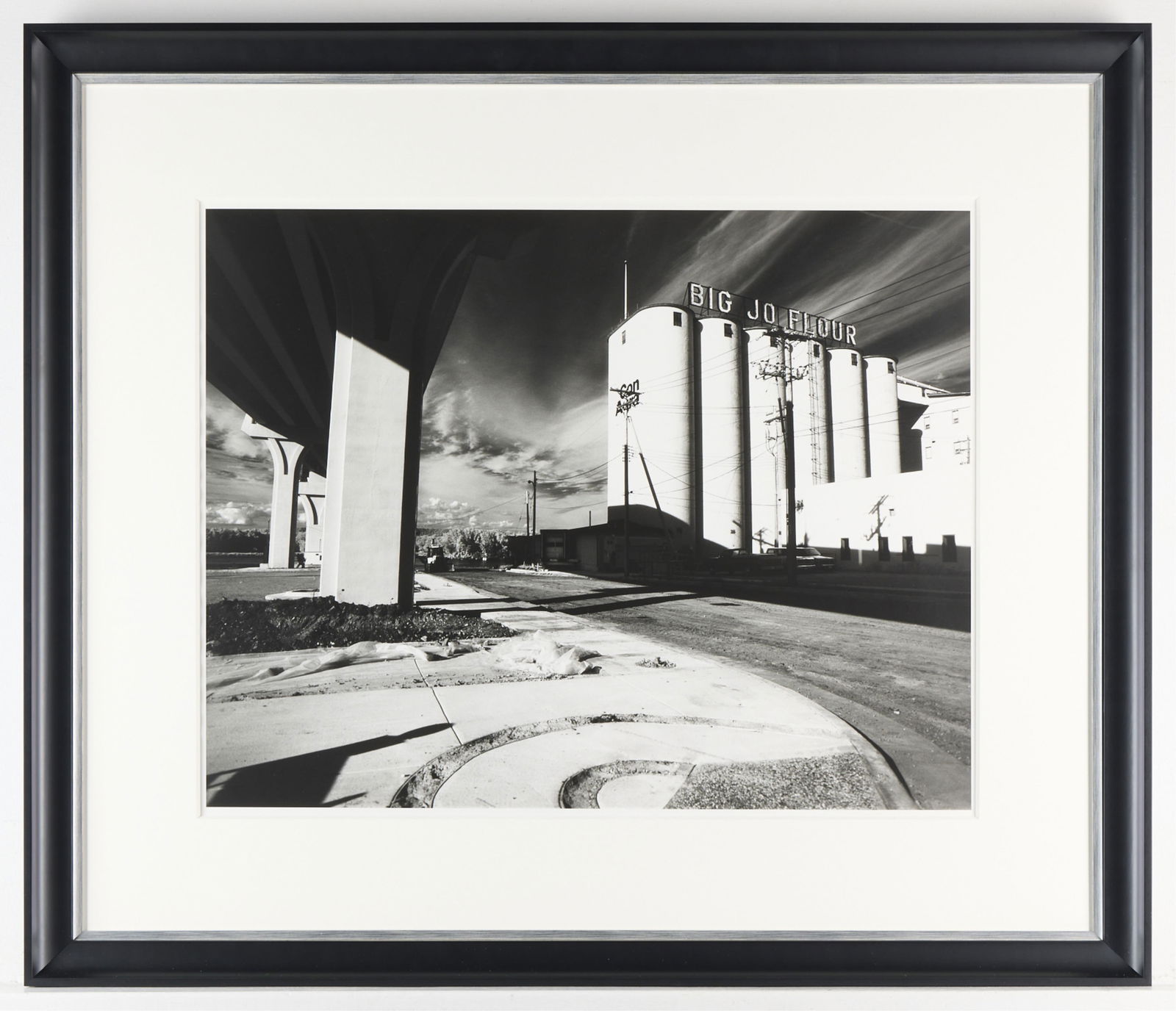 Ann Ginsburgh Hofkin "Wabasha" B&W Photograph: Silver gelatin print photograph in black and white. Depicting the Big Jo Flour Mill in Wabasha, Minnesota. Signed and titled along the verso. Height: 28 1/2 in x width: 33 1/2 in x depth: 1 1/4 in.
