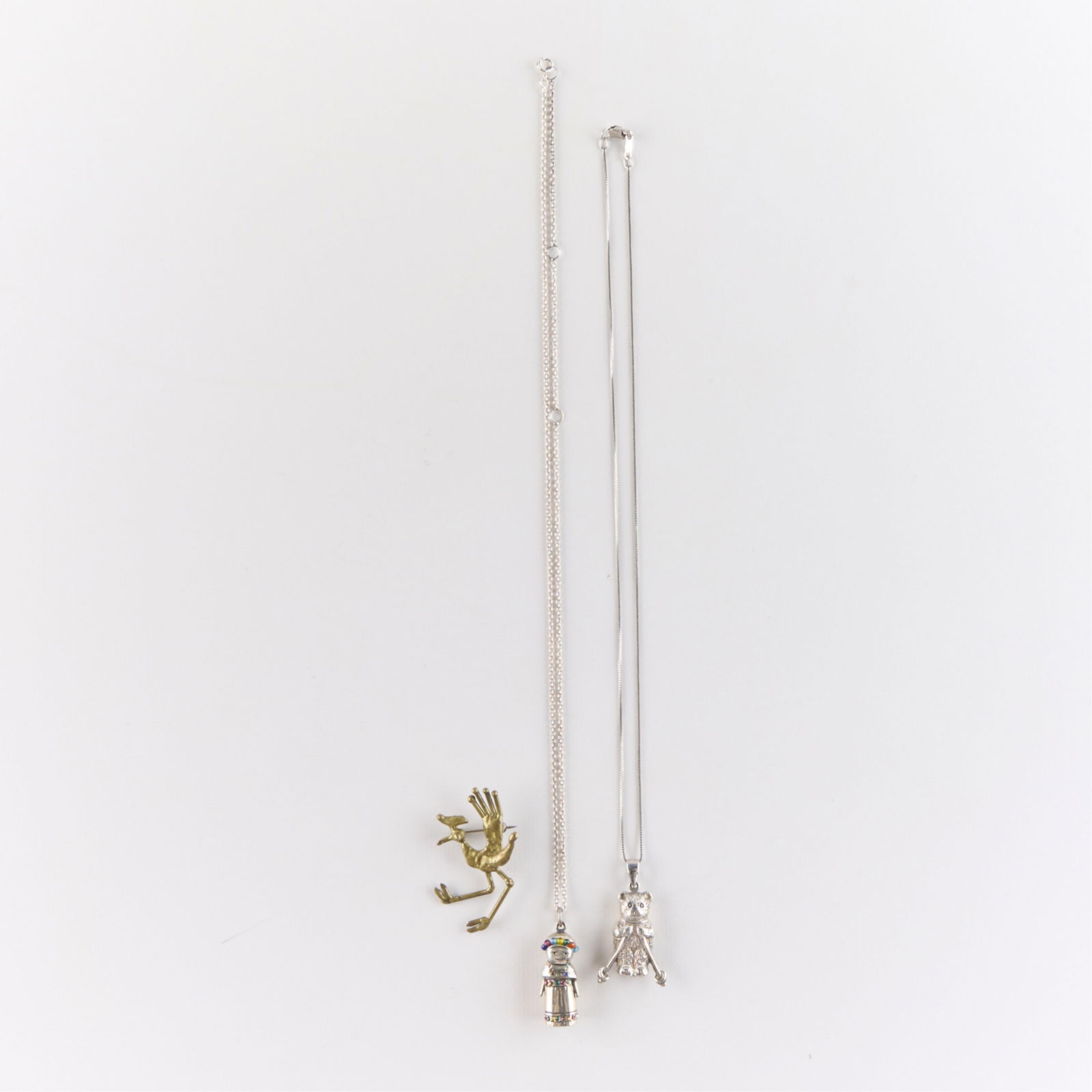 3 Pcs Sterling & Other Figural Jewelry: Including one 925 sterling silver necklace featuring a skiing bear pendant, one silver-toned necklace featuring a doll pendant decorated with multicolored paste gems, and one metal brooch pin in the