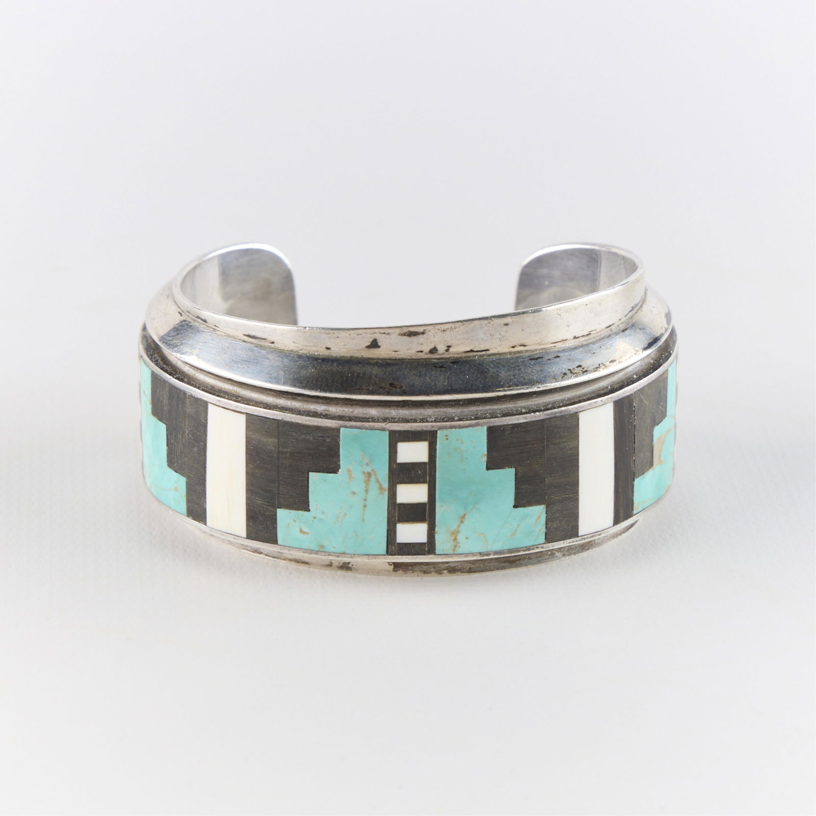 Zuni Silver Bangle: Zuni style silver bangle with inlaid harstones. Marked Daro. Unmarked, tested silver. Inner diameter: 2 1/4 in. Gross weight: 89.5 g.