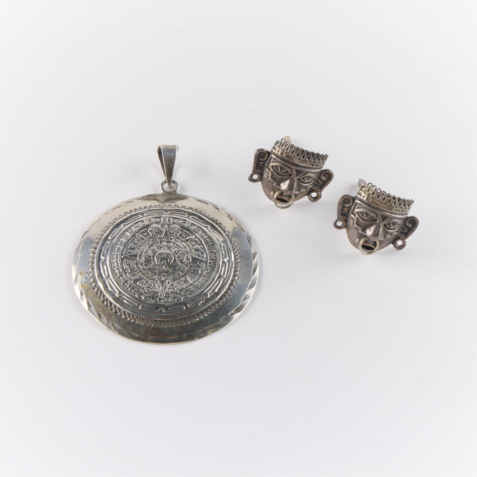 Pr Mexican Sterling Silver Earrings & Pendant: Including one pair of cufflinks depicting Aztec warrior masks, and one pendant depicting the Mesoamerican Aztec or Mayan sun calendar. All marked. Gross weight: 27.72 g.