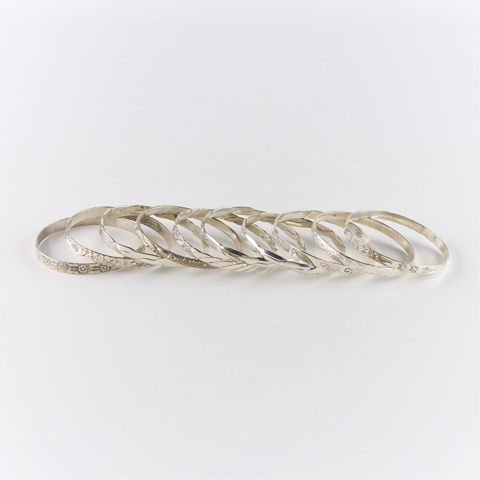 10 Taxco Mexican Silver Bangles - 160 g: Group of ten Mexican silver bangles. Some with engraved designs. Each marked "Taxco Mexico" or "Mexico." (Each) Diameter: 2 1/2 in. Gross weight: 160.4 g.