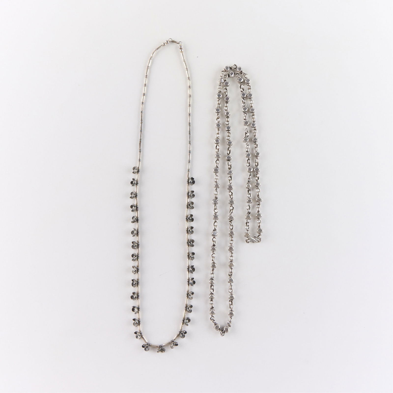2 Large Silver Necklaces: 2 large silver necklaces including one with cannetille flowers and a heavy necklace with decagon beads. Both unmarked and tested indicated silver. Length ranges from 30 in to 33 in. Gross weight: