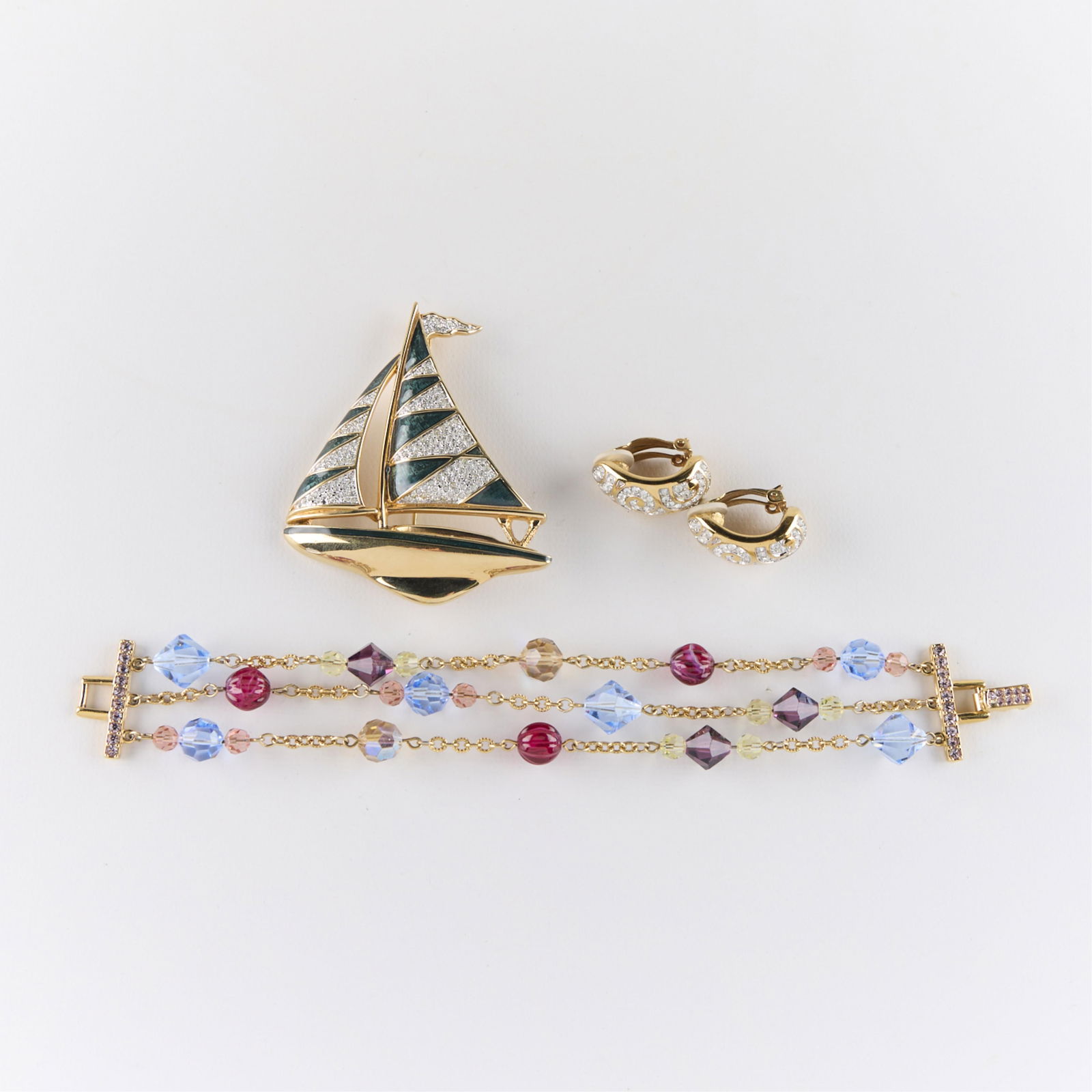 3 Pcs Swarovski Costume Jewelry: Including one multi-strand bracelet, one brooch pin in the form of a sailboat, and one pair of earrings. Each marked. (Bracelet) Length: 8 1/2 in. (Brooch) Height: 3 in x width: 2 1/2 in x depth: 1/2