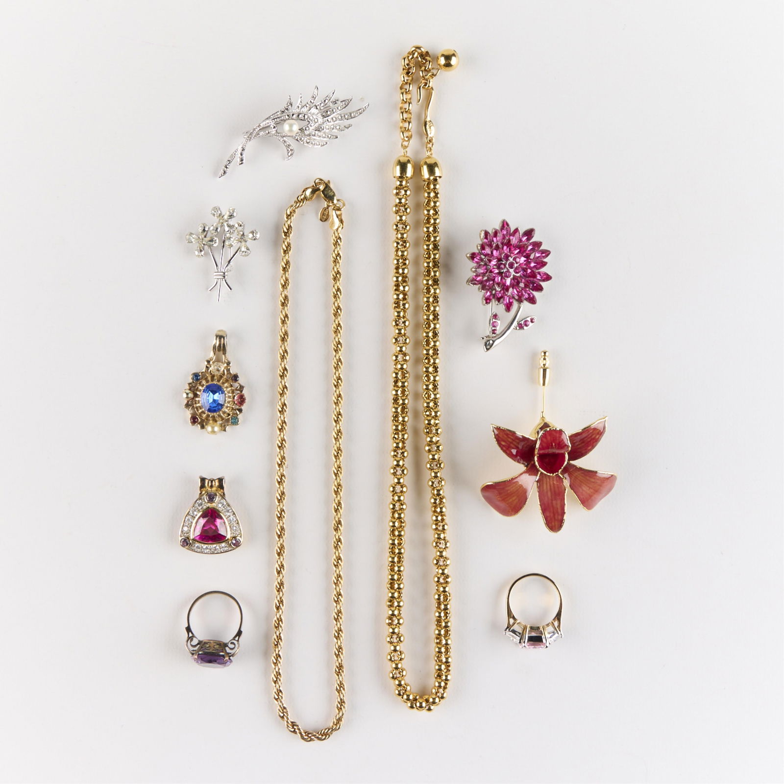 10 Pcs Sterling, Gold-Toned, & Silver-Toned Jewelry: Group of ten gold- and silver-toned costume jewelry pieces. Including one sterling Phyllis floral brooch, marked, one sterling pendant with inlaid pink gemstone, one brooch in the form of a blooming