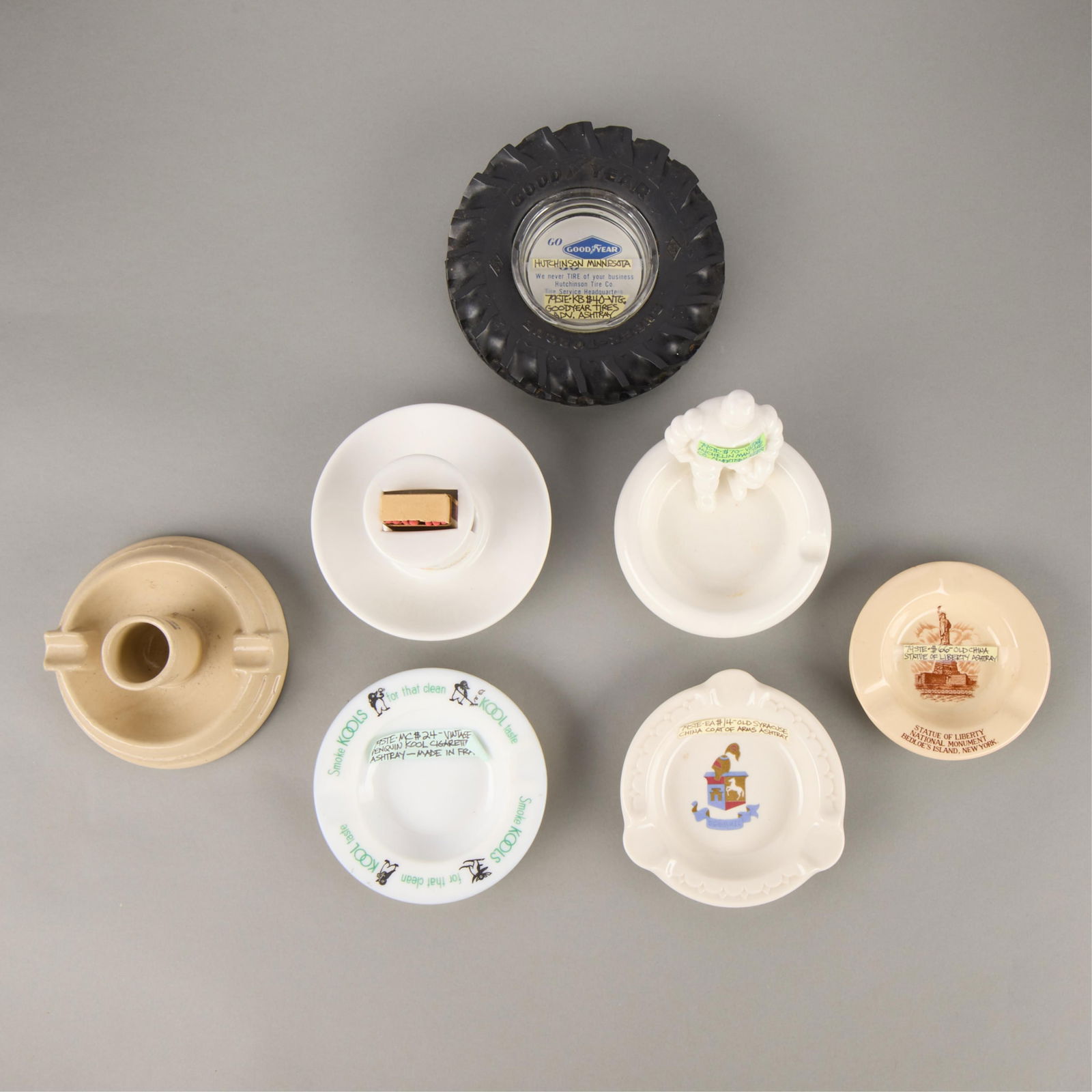 7 Vintage Advertising & Decorative Ashtrays: Group of seven assorted vintage advertising and decorative ashtrays. Composed of ceramic, glass, and rubber. Including advertisements for Kool Cigarettes, the Michelin Man Tire Company, Goodyear Tires