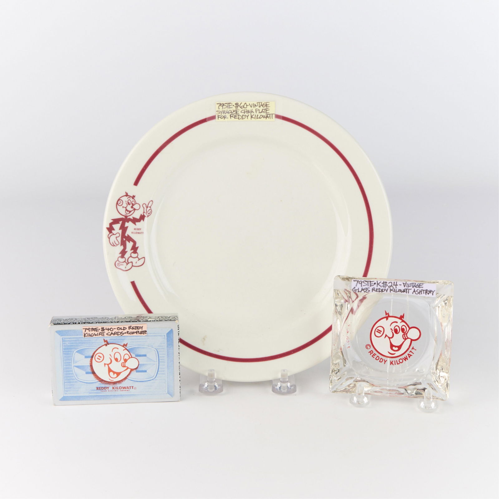3 Pcs Reddy Kilowatt Advertising Ephemera - Plate, Ashtray, & Cards: Group of three pieces of advertising ephemera related to the vintage cartoon electrical servant, Reddy Kilowatt. Including one vitrified porcelain plate, one glass ashtray, and one set of playing card