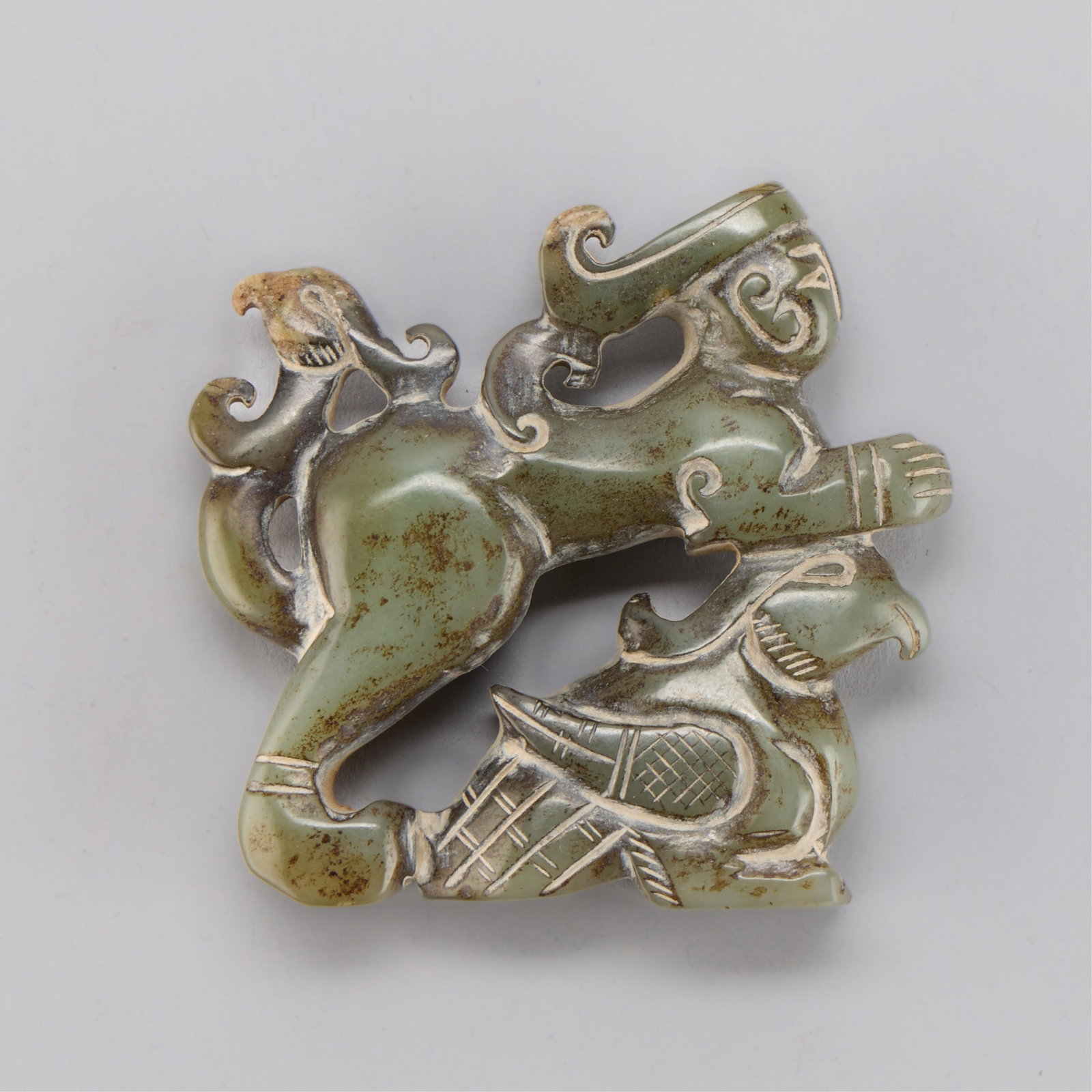 Chinese Archaic Style Jade Carving: Chinese jade or jadeite archaistic style pendant in the form of mythical bird-like creatures. Height: 2 1/2 in x width: 2 1/2 in x depth: 1/2 in. Weight: 80.92 g.