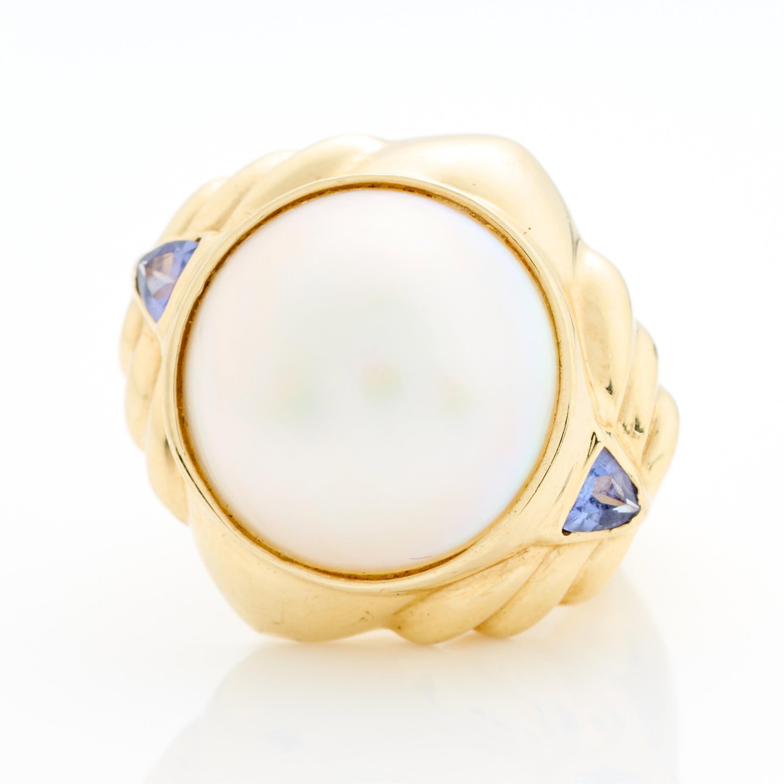 14k Yellow Gold Mabe Pearl Ring Sz 7: 14k yellow gold ring set with large mabe pearl and two trillion cut accent stones, possibly tanzanite. Marked 14k along the interior. Ring size: 7 US. Gross weight: 14.99 g
