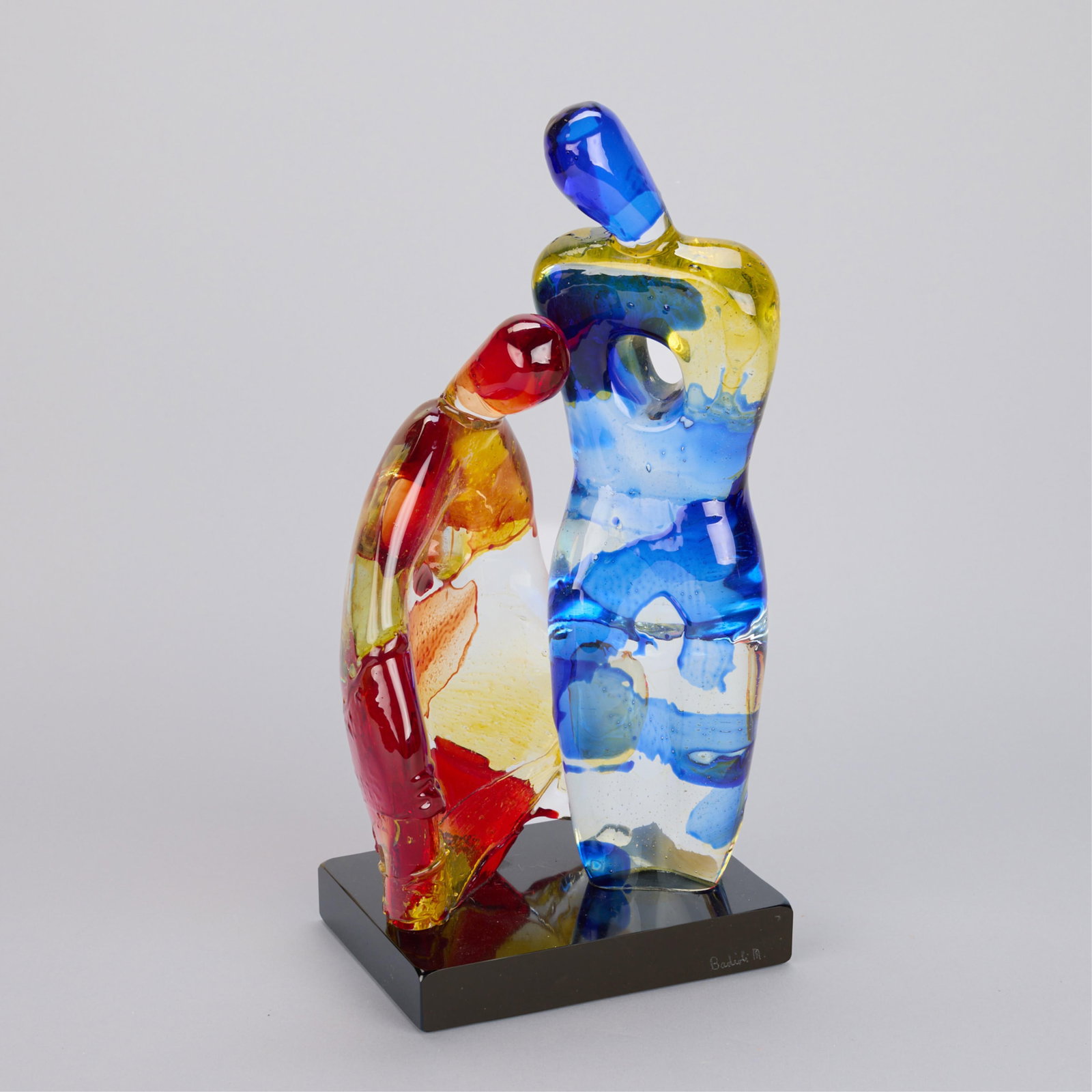 Mario Badioli "Two Figures" Murano Glass Sculpture: Mario Badioli (Italian, b. 1940). Murano art glass sculpture depicting two abstract figures, one blue and one red. Mounted atop a black stone base. Incised signature along the base. Height: 15 3/4 in 
