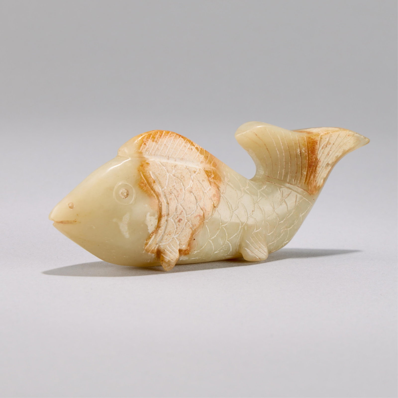 Chinese Carved Jade Fish: Chinese carved jade fish with lovely russet inclusions. Drilled hole through the nostrils to be worn as a pendant. Height: 1 5/8 in x width: 3 3/4 in x depth: 1 in. Weight: 81.21 g.