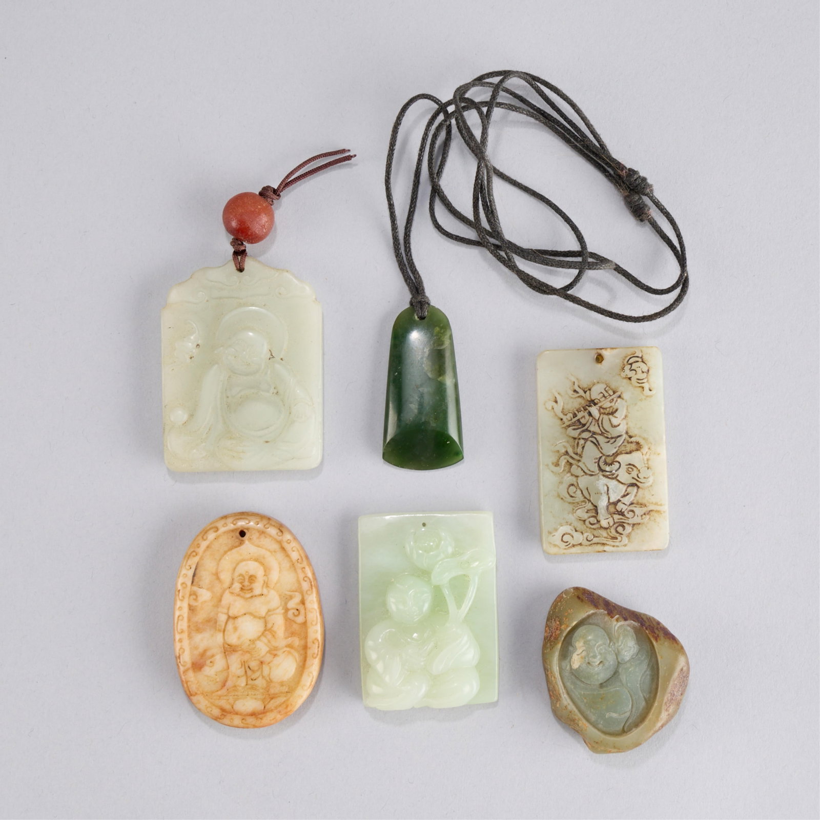 6 Chinese Jadeite Buddha Pendants: Group of six Chinese jade or jadeite pendants; five carved with Buddha figures. One in the form of an ax head. Height ranges from 1 5/8 in to 2 1/8 in; width ranges from 3/4 in to 1 1/2 in; depth rang