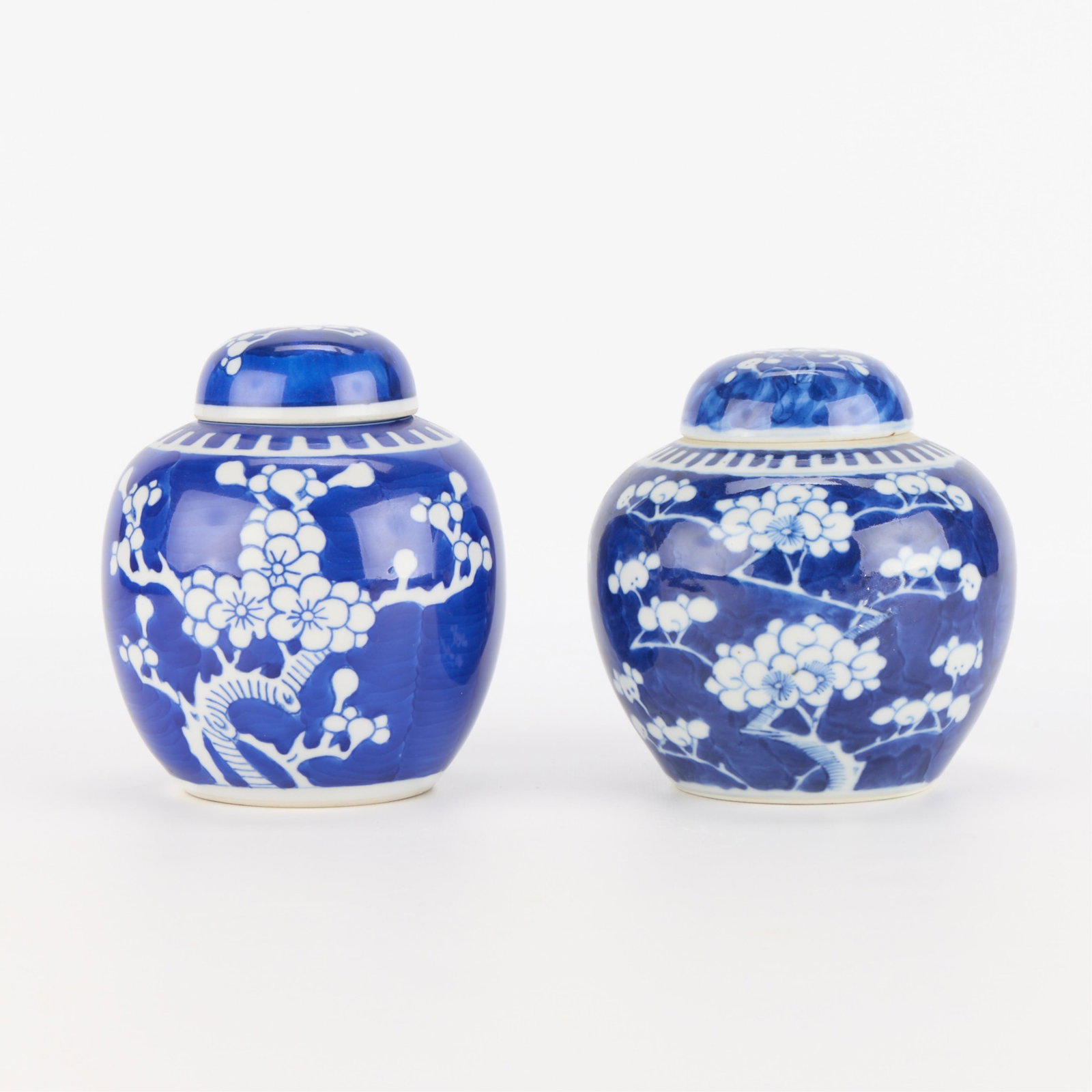 2 Chinese Blue & White Porcelain Prunus Ginger Jars: Group of two Chinese blue and white porcelain ginger jars or vases depicting a prunus motif. Each with an apocryphal Kangxi double blue circle mark along the underside. (Each) Height: 6 1/4 in x