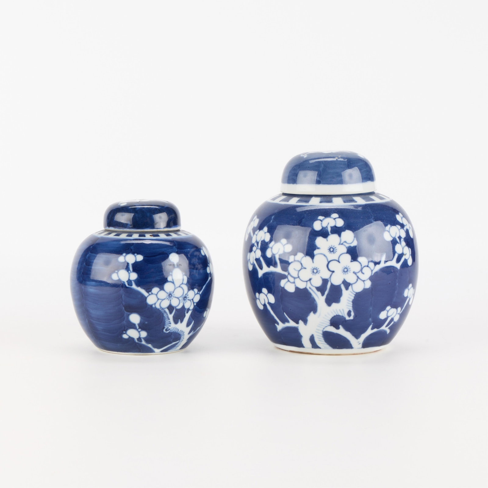 Grp 2 Chinese Blue & White Porcelain Ginger Jars: Group of two Chinese blue and white porcelain ginger jars depicting prunus motifs along the body of the vessel. Both with lids and an apocryphal Kangxi double blue circle mark along the underside.