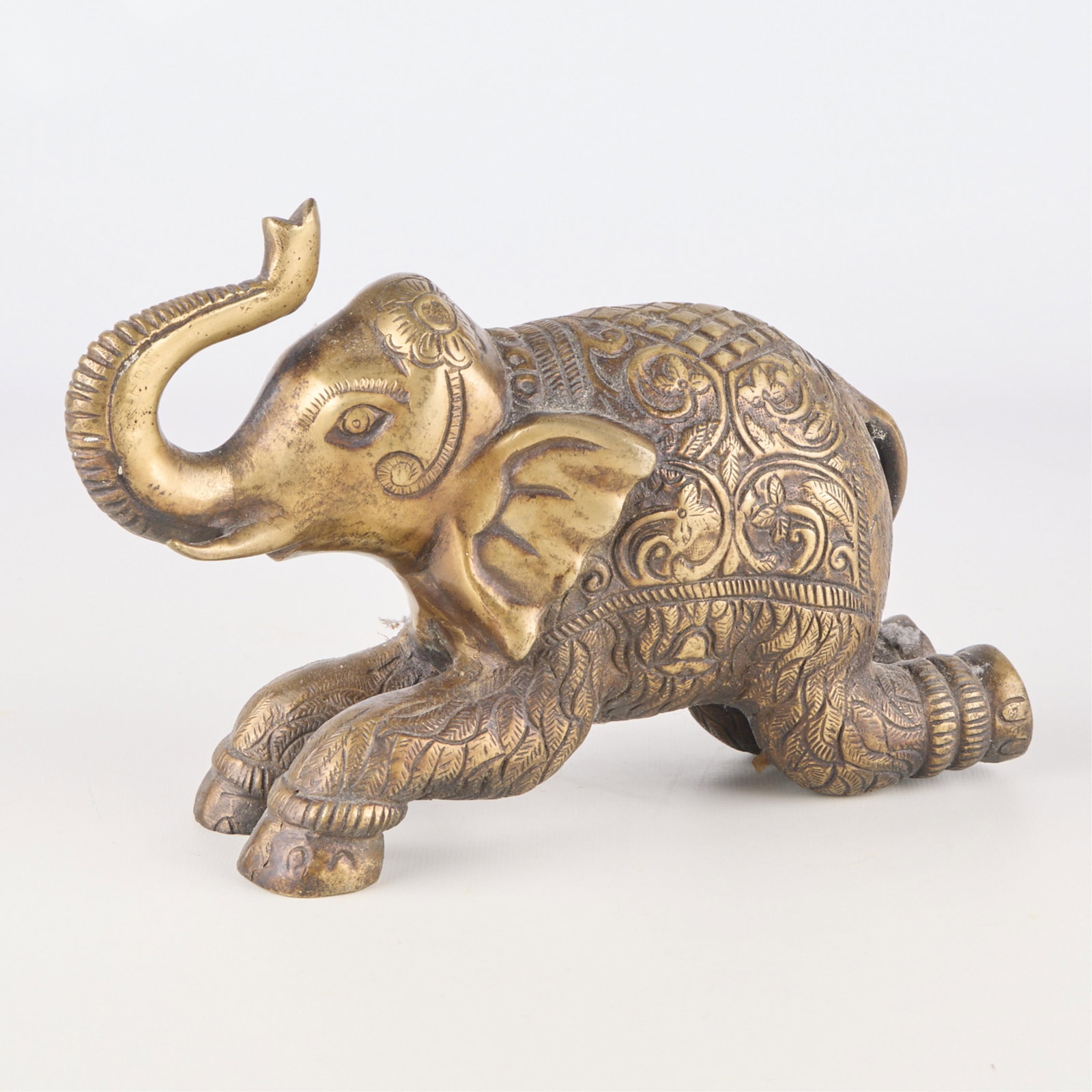 Likely Indian Ornate Brass Kneeling Elephant: Ornate brass kneeling elephant. Likely Indian. Height: 6 1/2 in x width: 9 in x depth: 3 1/2 in. Weight: 4 lbs 11 oz.