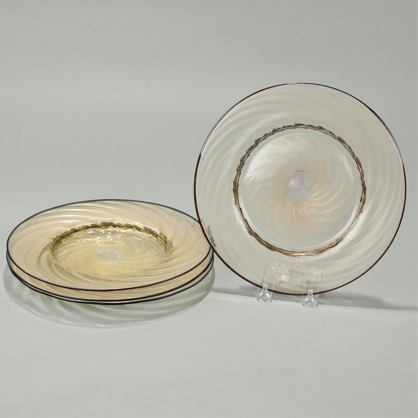 4 Glass Gilt Spiral Dinner Plates: Group of four art glass dinner plates. Decorated with gilt spiral pattern, black rims, and raised ruffled footrim. (Each) Diameter: 10 1/2 in.