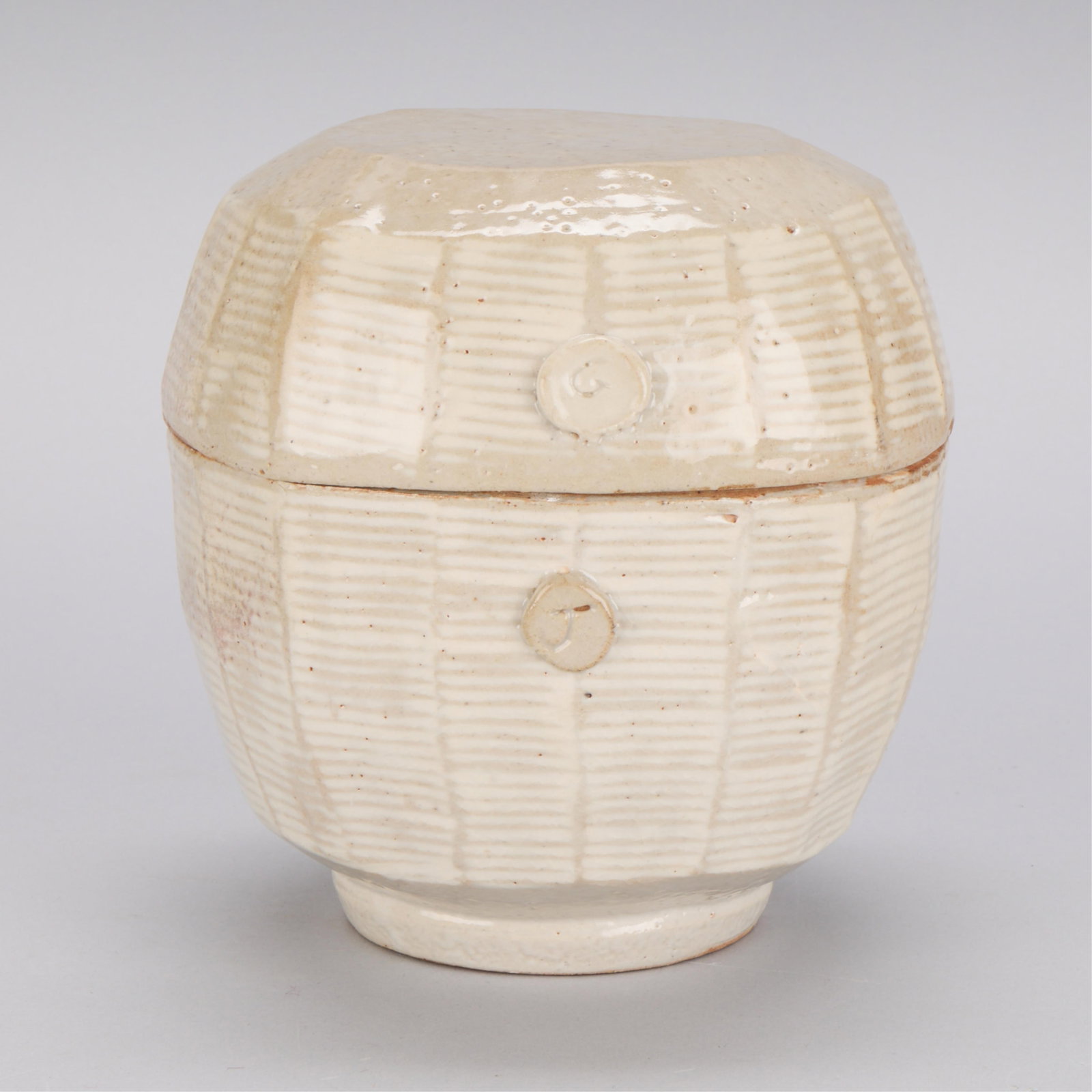 Studio Pottery Lidded & Faceted Jar - Signed "GJ": Studio pottery lidded and faceted jar. With two incised intials, reading "G" along the lid and "J" along the vessel. Resting on a recessed foot. Height: 7 1/2 in x diameter: 7 in.