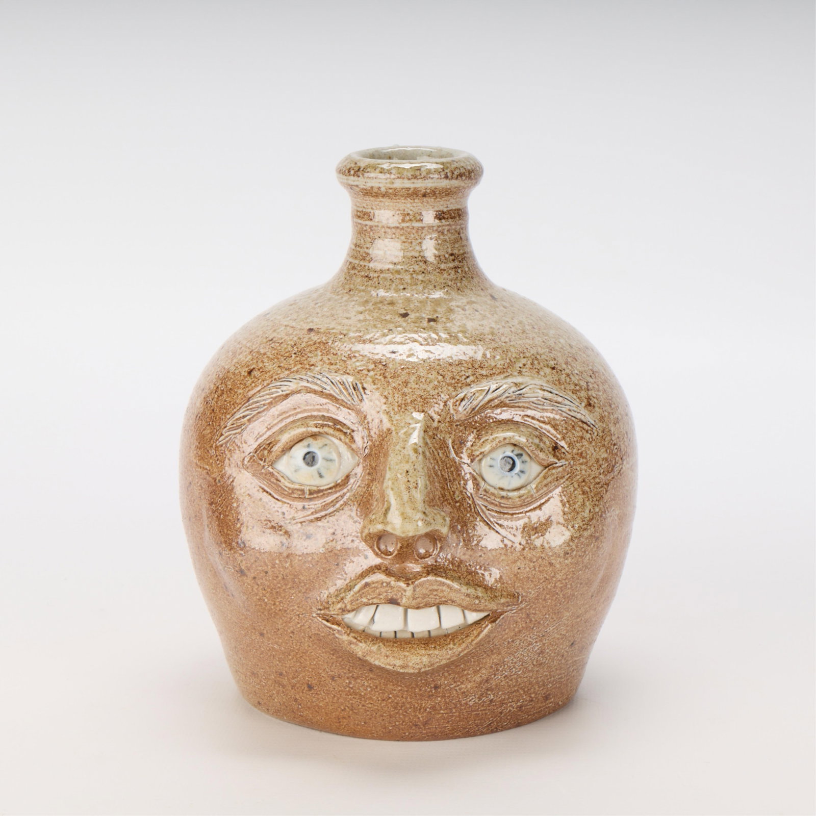 Southern Folk Art Pottery Face Jug - Marked: Southern American folk art pottery face jug, 20th century. Similar in style to Reggie and Lanier Meaders pottery. With artist's seal along the base of the handle, reading "TCC." Height: 7 1/4 in x wid