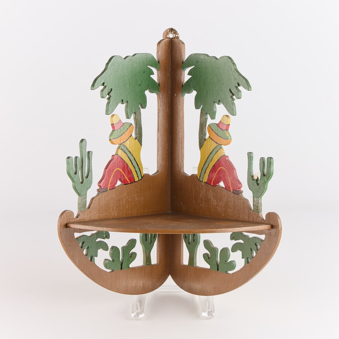 Vintage Mexican Folk Art Painted Wood Corner Shelf: Vintage Mexican folk art wood and pigment corner shelf depicting two campesino men below trees amid cactus, 20th century. Height: 16 1/2 in x width: 12 1/2 in x depth: 9 in.