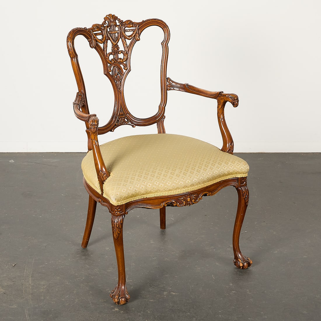 Antique Carved Colonial Style Arm Chair: Antique colonial-style armchair with an intricately carved backsplat depicting foliate and faunal motifs, and a floral upholstered seat. Height: 37 1/2 in x width: 25 in x depth: 21 in.
