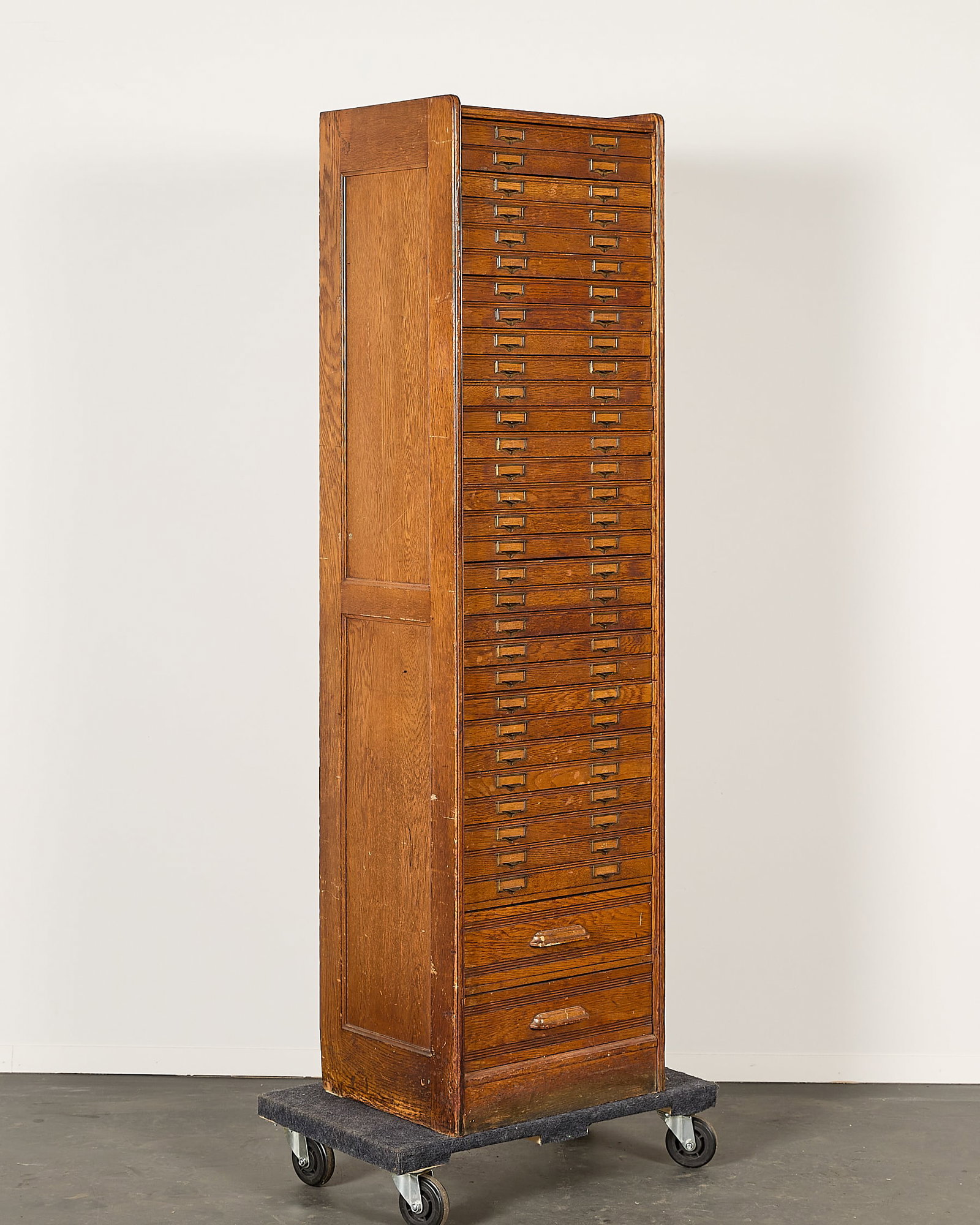 Antique Oak File Cabinet w/ 32 Drawers: Antique oak file cabinet with 32 drawers. Featuring numerous small drawers with brass hardware; two larger drawers along the bottom with wooden handles. Hieght: 74 in x width: 20 1/2 in x depth: 16