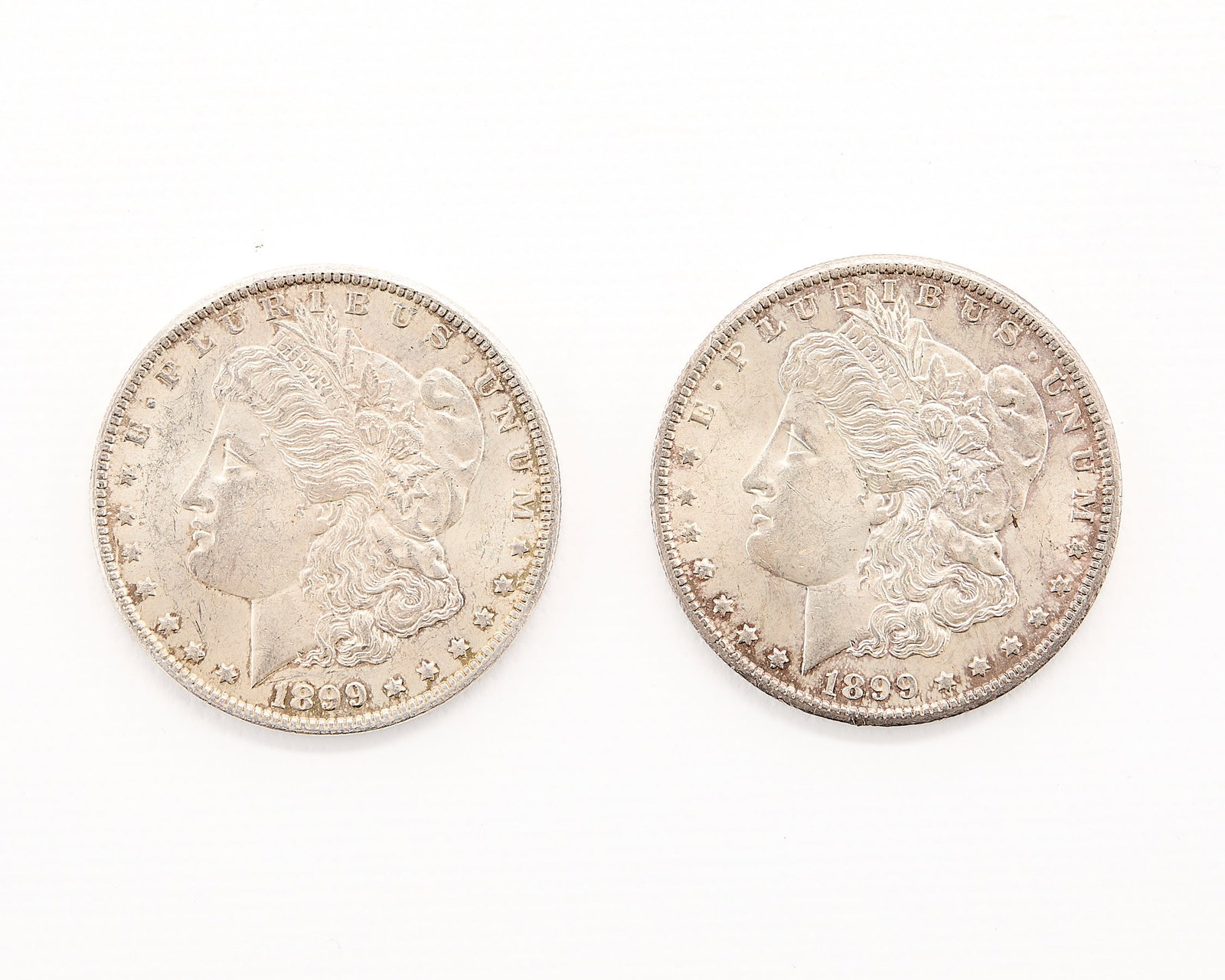 2 1899-O Morgan Silver Dollars: Group of two 1899-O Morgan silver dollar coins. Likely of AU or MS quality. (Each, approx.) Diameter: 38.10 mm. Weight: 26.73 g.
