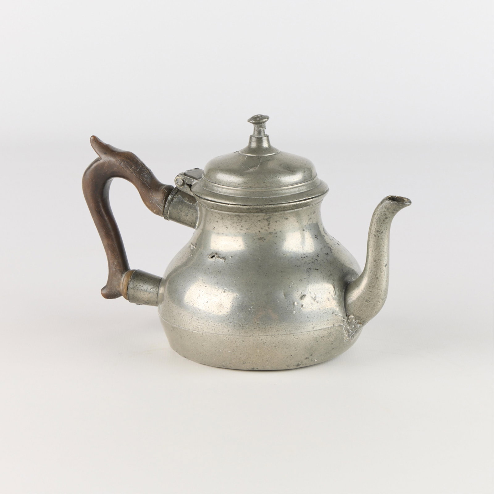 Antique Early American Pewter Teapot: Antique American pewter teapot of pear-shaped form. Similar in style to Queen Anne period vessels, popular during the early 18th century. With carved wooden handle. Etched initials along the interior