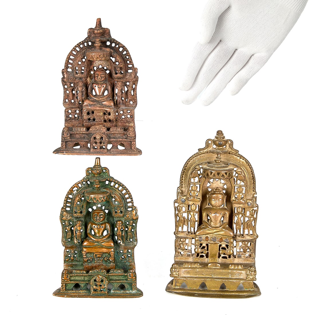 3 Indian Bronze Jain Alter Shrines: Group of three Indian bronze Jain alter shrines. Each featuring a central Tirthankara figure seated in meditation surrounded by intricate architectural details resembling a temple facade. Each with