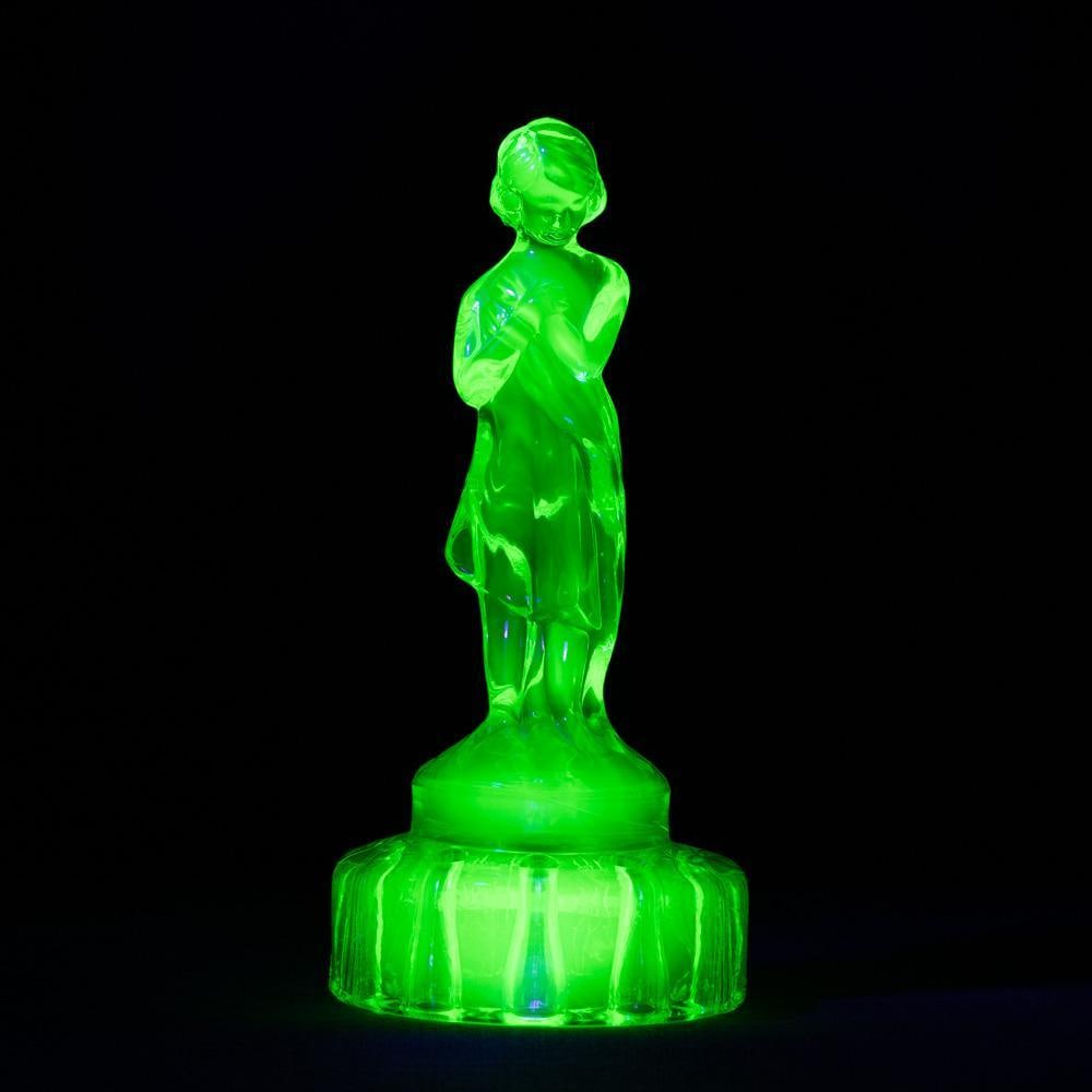 Cambridge Uranium Glass 8 1/2 Inch Draped Lady Flower Frog: A vintage 1920-30's Art Deco green uranium glass flower frog, the frog base topped with a nude female figure clasping drapery to her body. Made by Cambridge Glass Company, Ohio. 8 1/2 inches tall. Low
