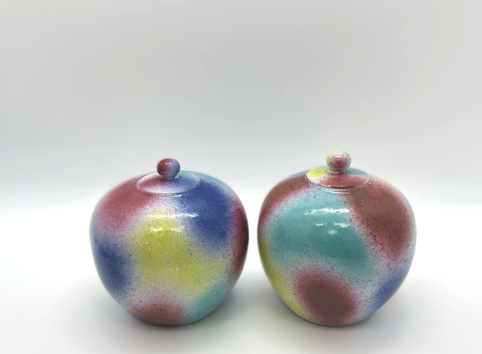 A Chinese Rainbow Glazed Covered Jars (Pair)19TH.C: The jars have a simple,19th, rounded form with matching lids, and the glaze transitions smoothly between shades of pink, blue, yellow, and green, creating a playful.Height: 4.33''Provided by the Zhang