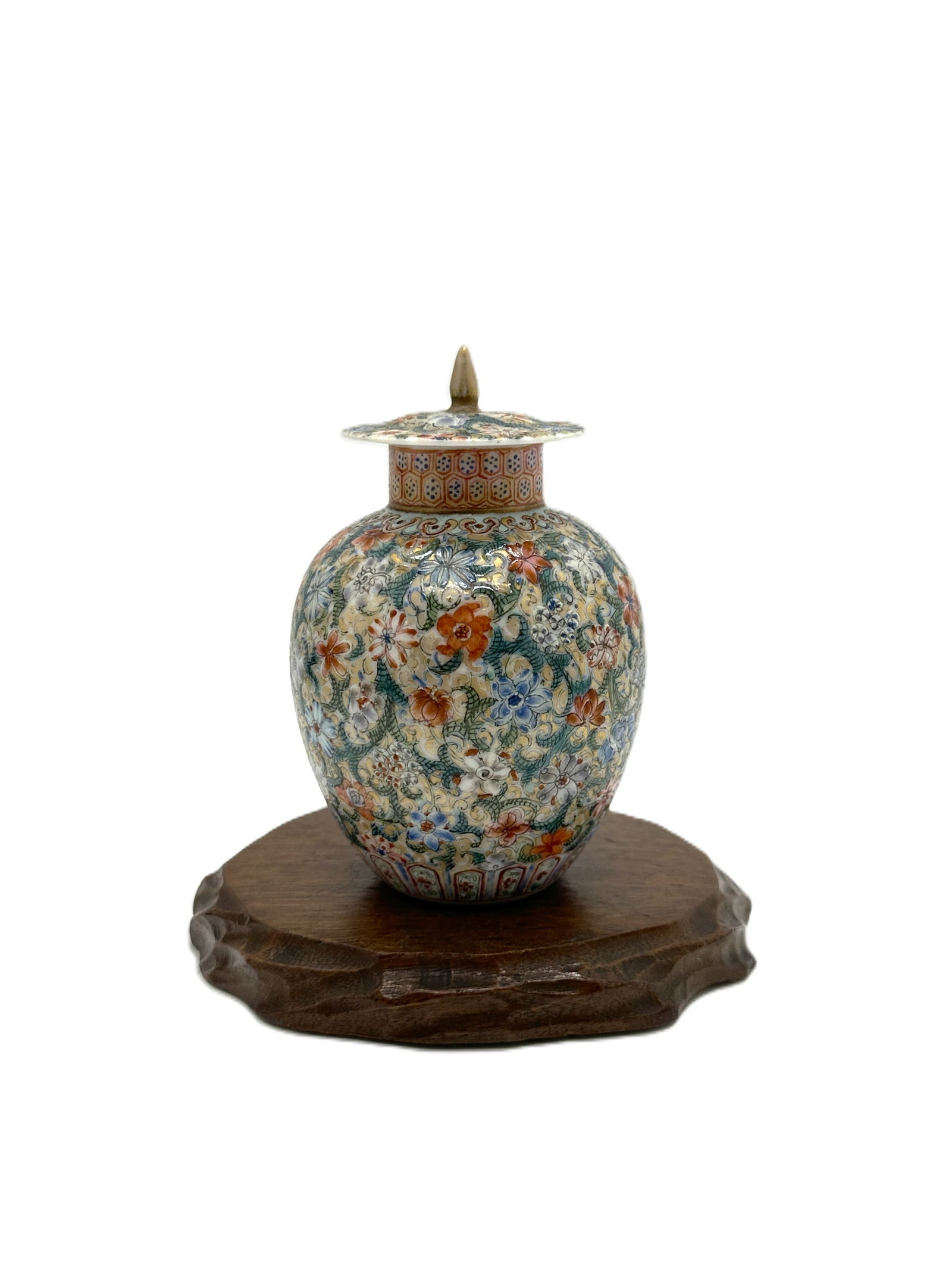 Famille Verte 'Millefleur' Covered Jar on Stand.China: A delicate antique Chinese Famille Verte covered ginger jar or small urn. It's exuberantly decorated with a 'millefleur' (thousand flowers) pattern on a turquoise ground, resting on a carved wooden st