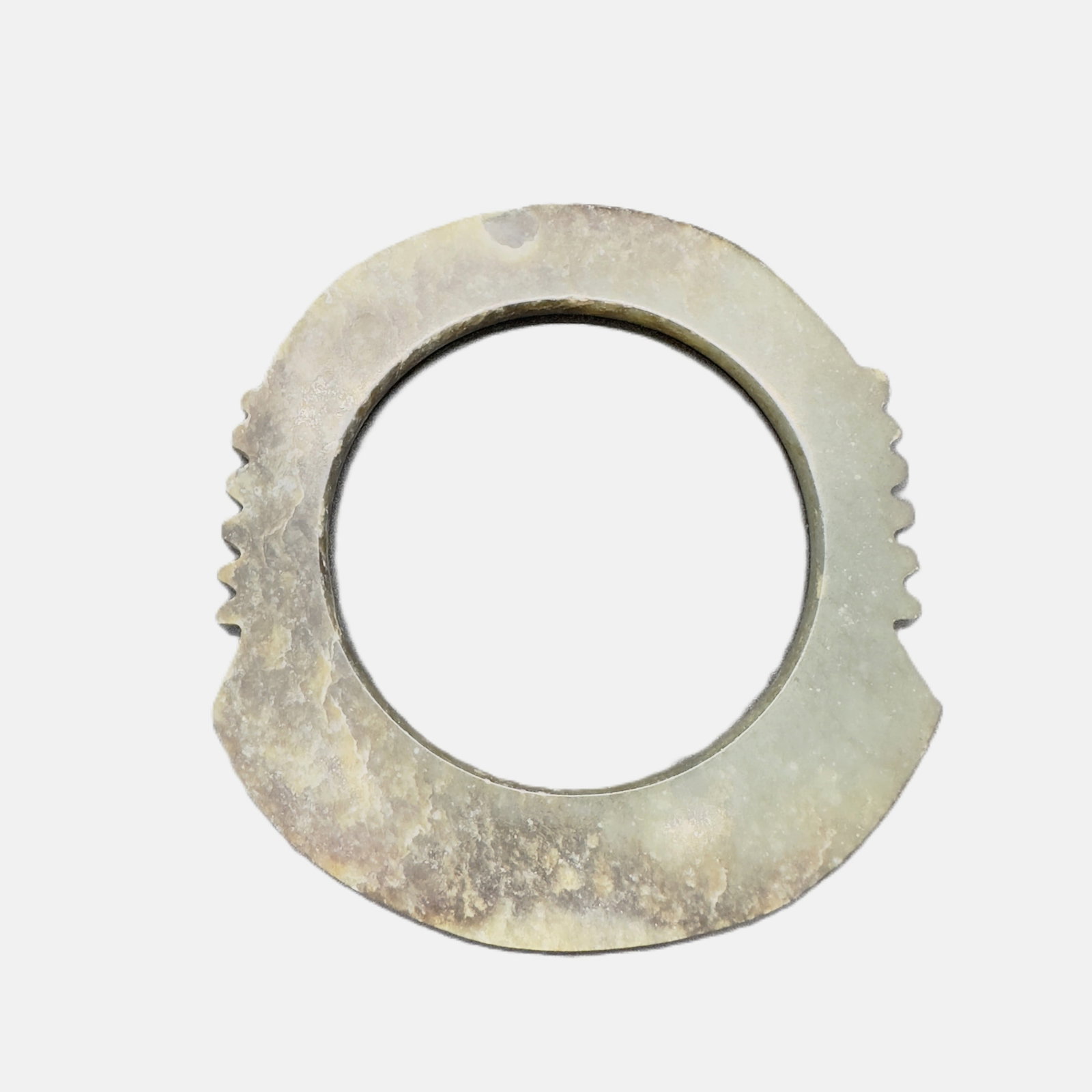 A Chinese Jade notched disc 'Xuanji' (475-221 BC): This circular jade ring features two sets of stepped notches on opposite sides, a distinctive feature of early ritual jade artifacts. Carved from pale celadon jade with natural brownish patina and wea