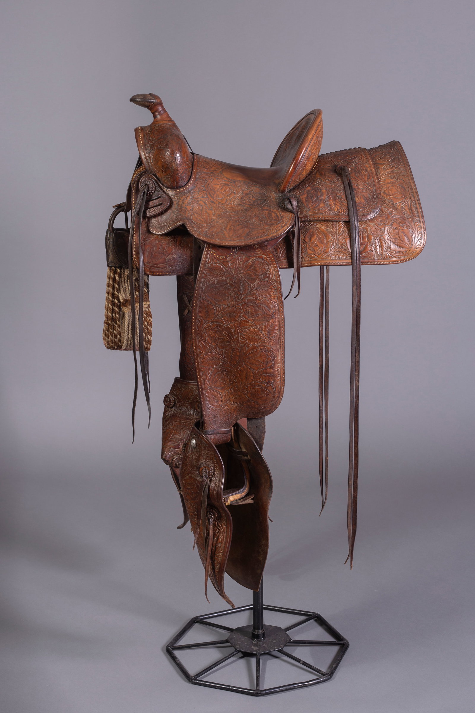 California Visalia Saddle, Ca. 1930s: California Visalia Saddle, D E Walker maker-marked, Floral toolilng with original cinch, 12" seat, 26" Skirt, Tapaderos stirrups, Ca. 1930s. Please note, stand not included.
