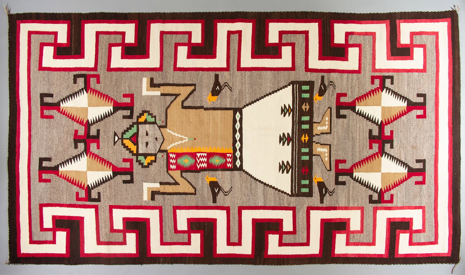 Navajo Kachina Rug, Ca. 1930s: Navajo Pictorial Yeii weaving depicting a Hopi Kachina image and four orange-headed blackbirds, Ca. 1930s. Down the side borders are bold, stylized interlocking whirling log motifs. The Kachina image 