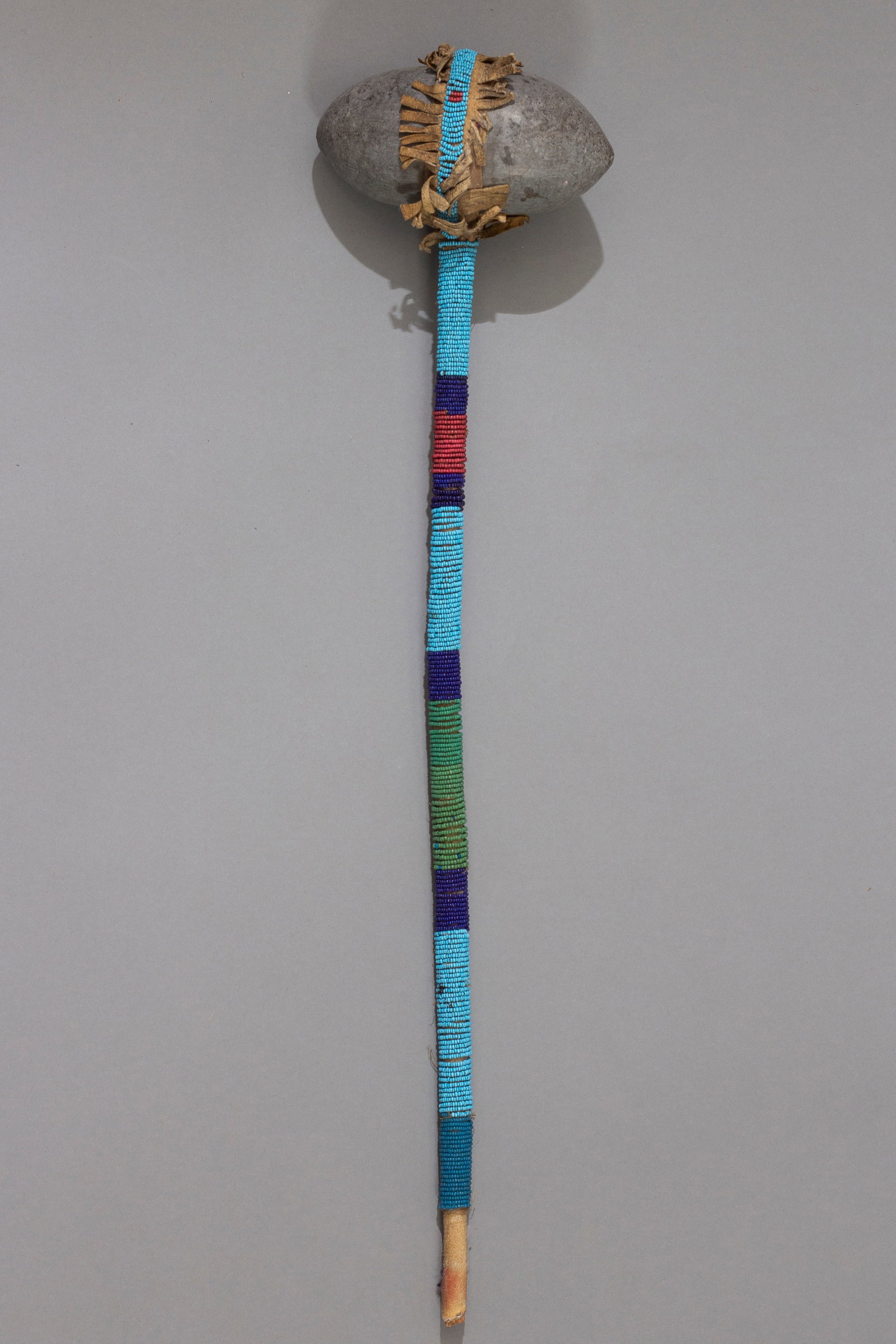 Sioux Beaded War Club, Ca. 19th Century: Sioux Beaded War Club, Ca. 19th century. Native American Hide and Stone Club, the rounded ovoid granite stone wrapped on the end of a hide-bound staff fully beaded with five variously colored bands wi