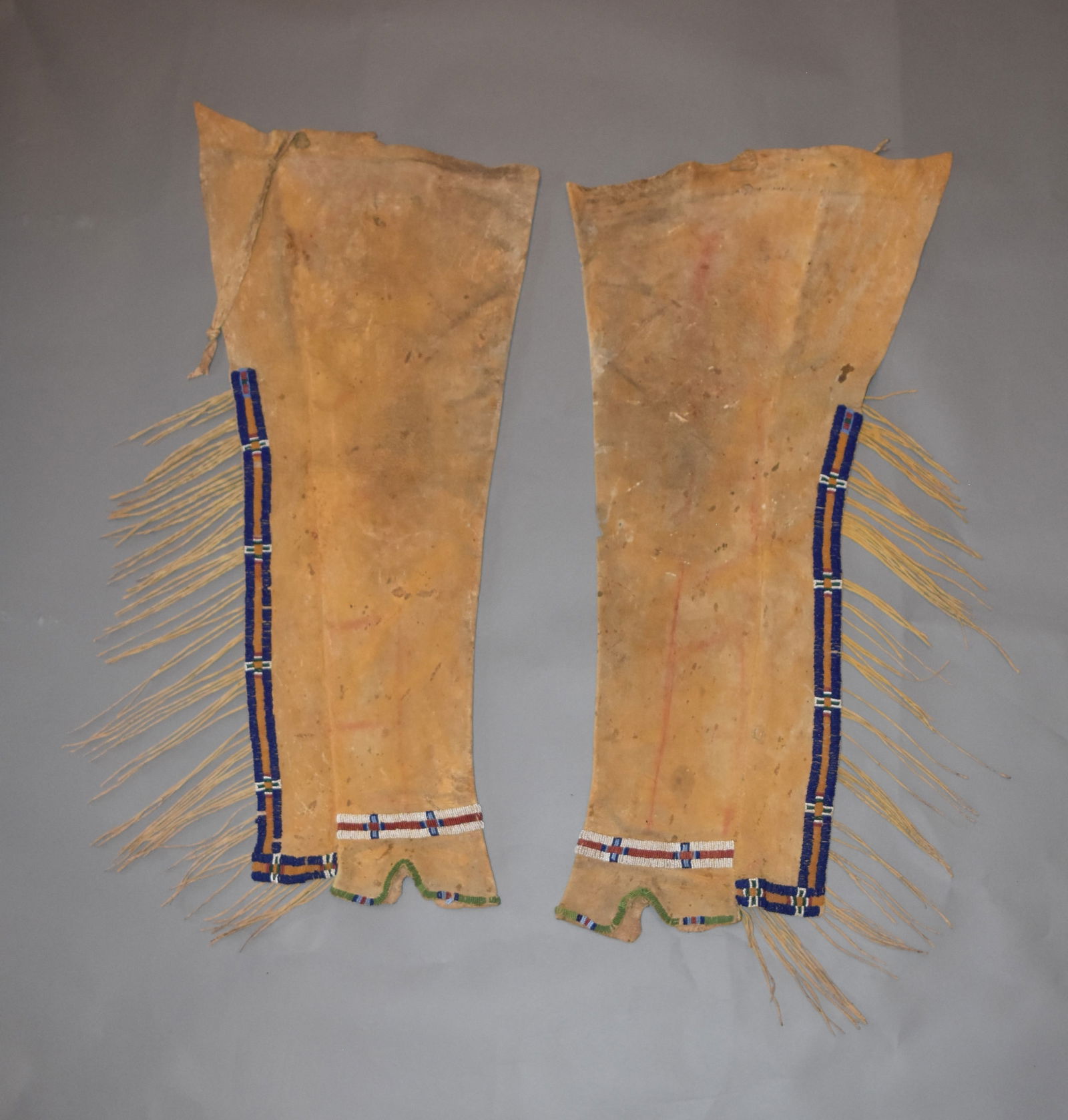 Southern Cheyenne or Arapaho Beaded Leggings, Ca. 1890s: Southern Cheyenne or Arapaho Beaded Leggings, Ca. 1890s. Tanned hide with dyed yellow ochre, beaded trim bands along edges in purple, light blue, red, yellow, green and white, long fringe runs length
