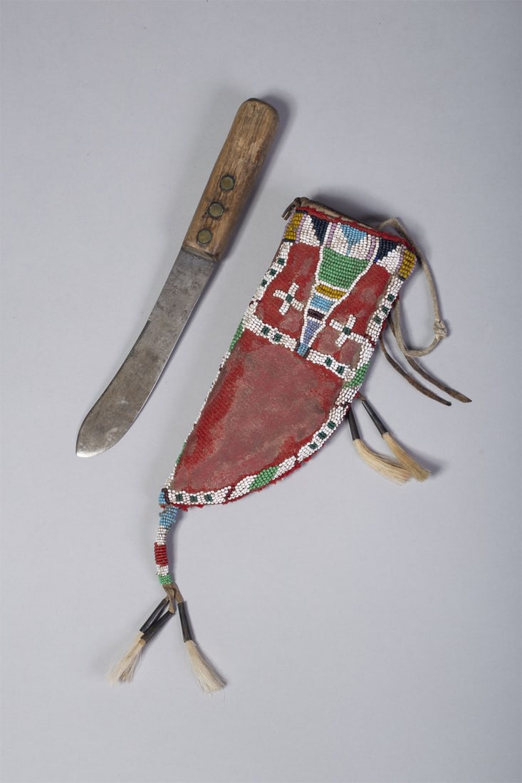 Sioux Knife Sheath with Knife: Sheath made of red trade cloth attached to thick hide and beaded with pink, yellow, white, navy, light blue, green and red beads. Beaded drop with cones and horsehair. Much of red trade cloth missing.