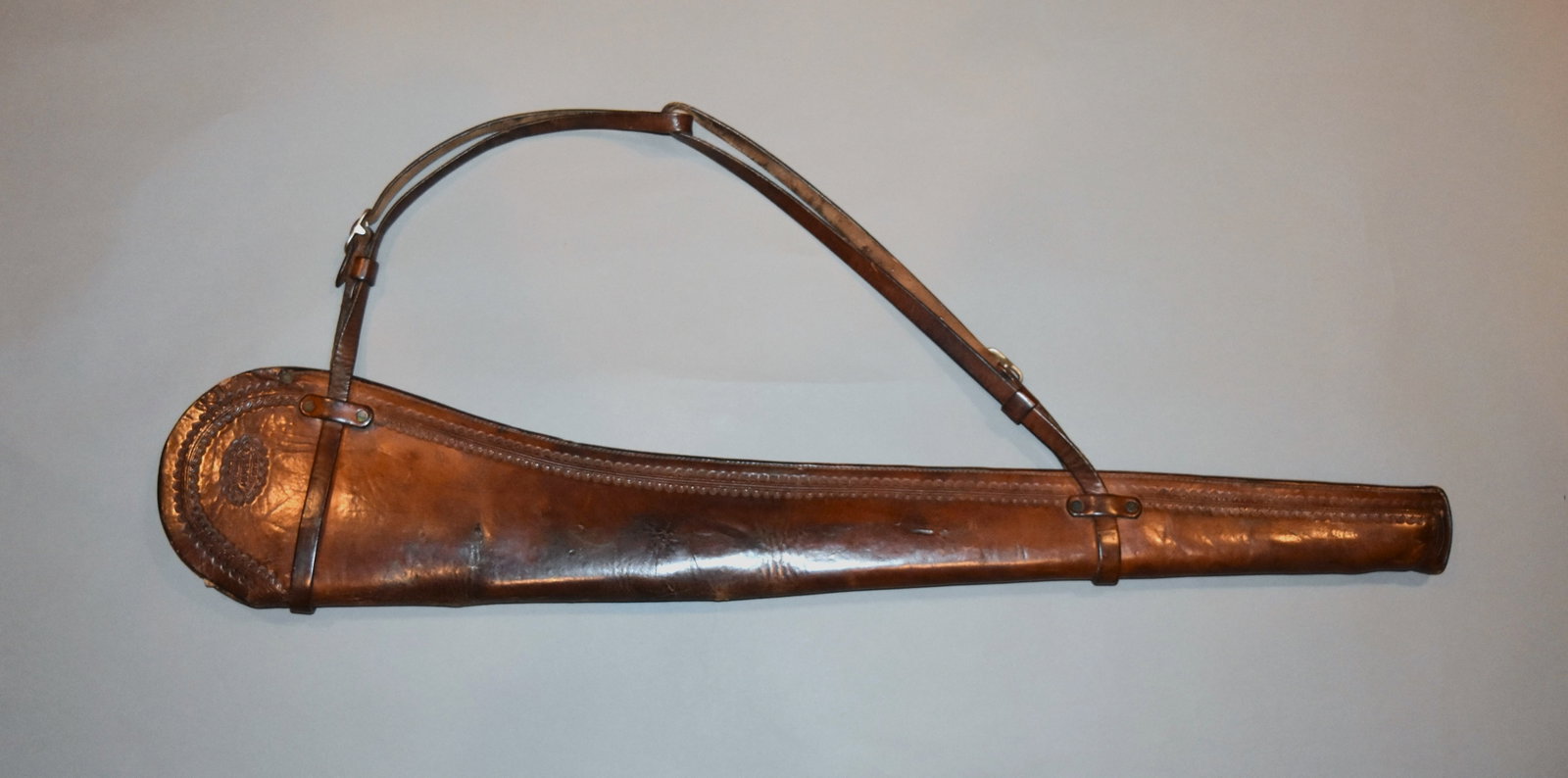 Miles City, MT marked Leather Gun Scabbard: Vintage "MILES CITY SADDLERY CO, MAKERS, MILES CITY, MONT" marked leather gun scabbard. Marked on both sides, half sunburst tooling around edge. Length: 35 1/4"