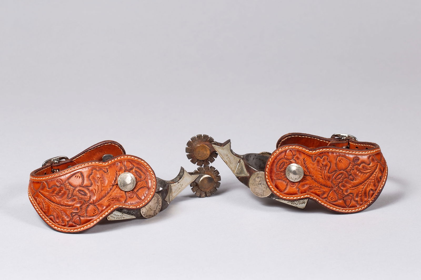 Texas Style Double mounted unmarked spurs with Silver Dollars and Indian Head Coins: Texas style made, double mounted with silver half dollars and silver inlay on heel band, Indian Head penny on rowel pin, with tooled leather straps and silver coin button, initials “GEK” on sh