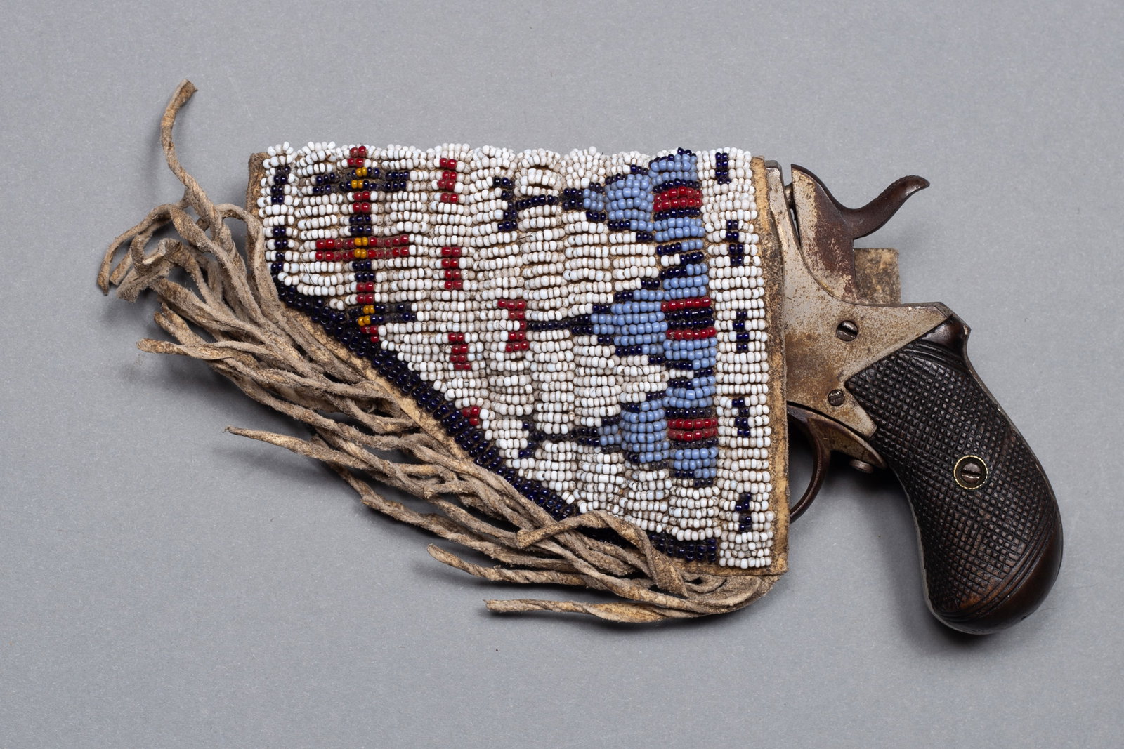 British Bulldog Revolver with Sioux beaded brain tanned holster: Marked “British, Bull-Dog” on top of frame, original walnut grips, 2 ¼” barrel, 6 shot, holster on hide has white beaded background with geometric designs in light blue, navy, yel