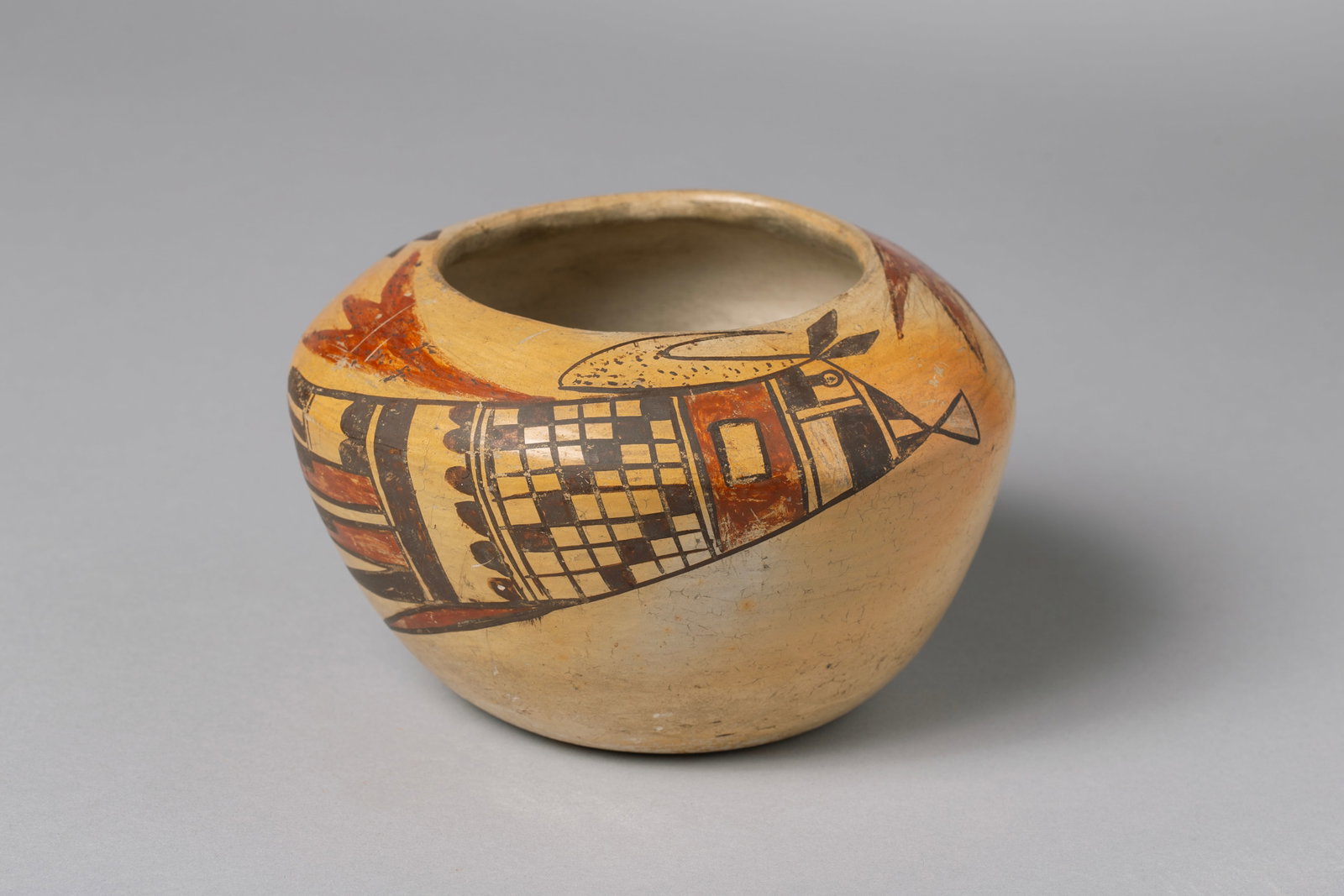 Hopi Polychrome Jar with Avian Design Elements: Low globular with slightly everted mouth, traditional Hopi warm yellow slip, featuring bird wing motifs containing checkerboard tail panels, scalloped dividers, stepped elements 4"H, 6 1/2"W