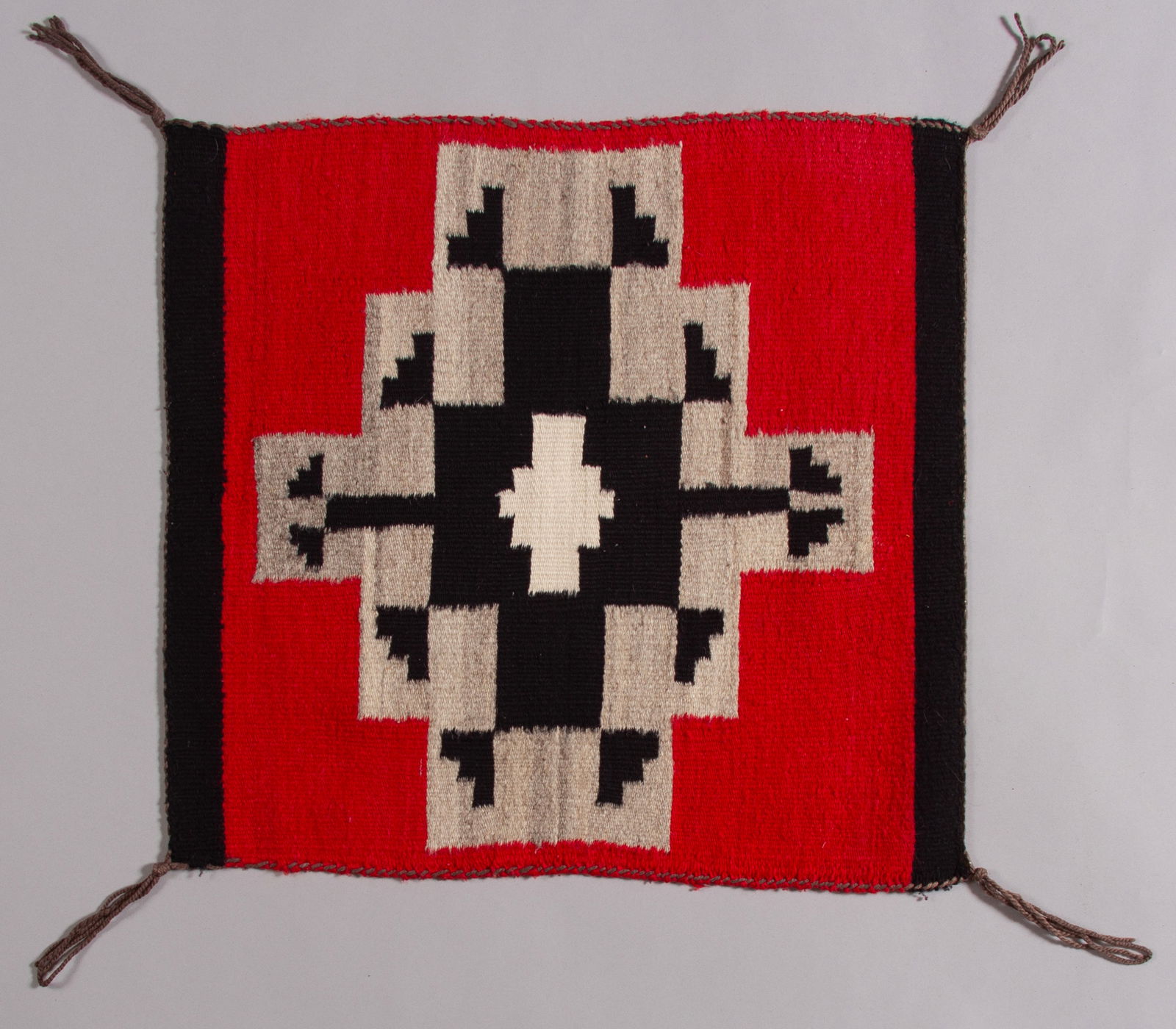 Navajo Rug, Ca 1960s: A sweet little miniature Navajo rug with a red field and black and grey stepped diamond medallion. Woven from all Native handspun and hand-dyed sheep wools. 24" x 21 1/2"