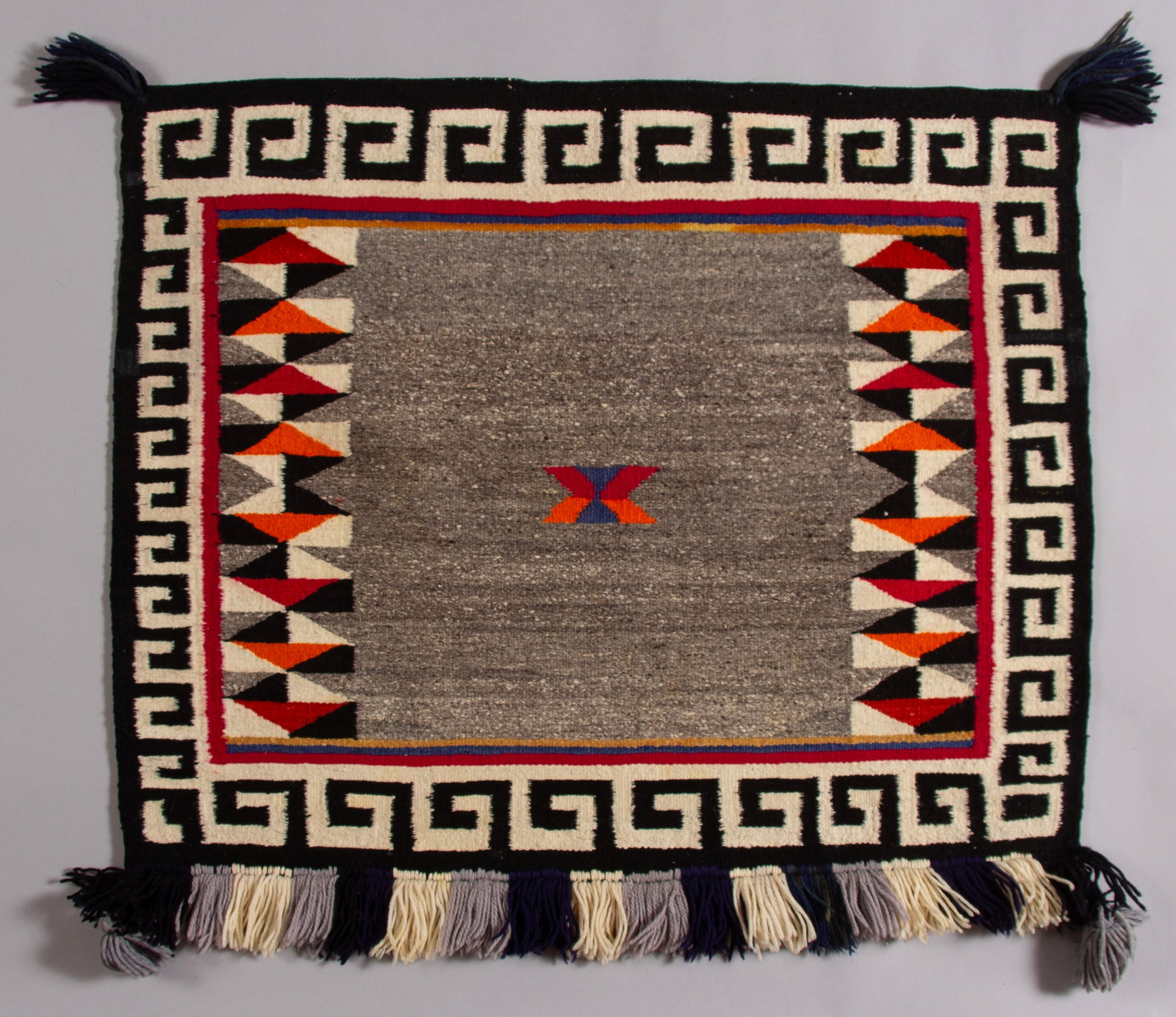 Navajo Rug Sunday Single Saddle Blanket, Ca 1940s: A very nice Sunday saddle blanket with an open field and a central colorful geometric motif. The borders are well executed and frame the field nicely. Nicley handwoven from all native handspun Churro 