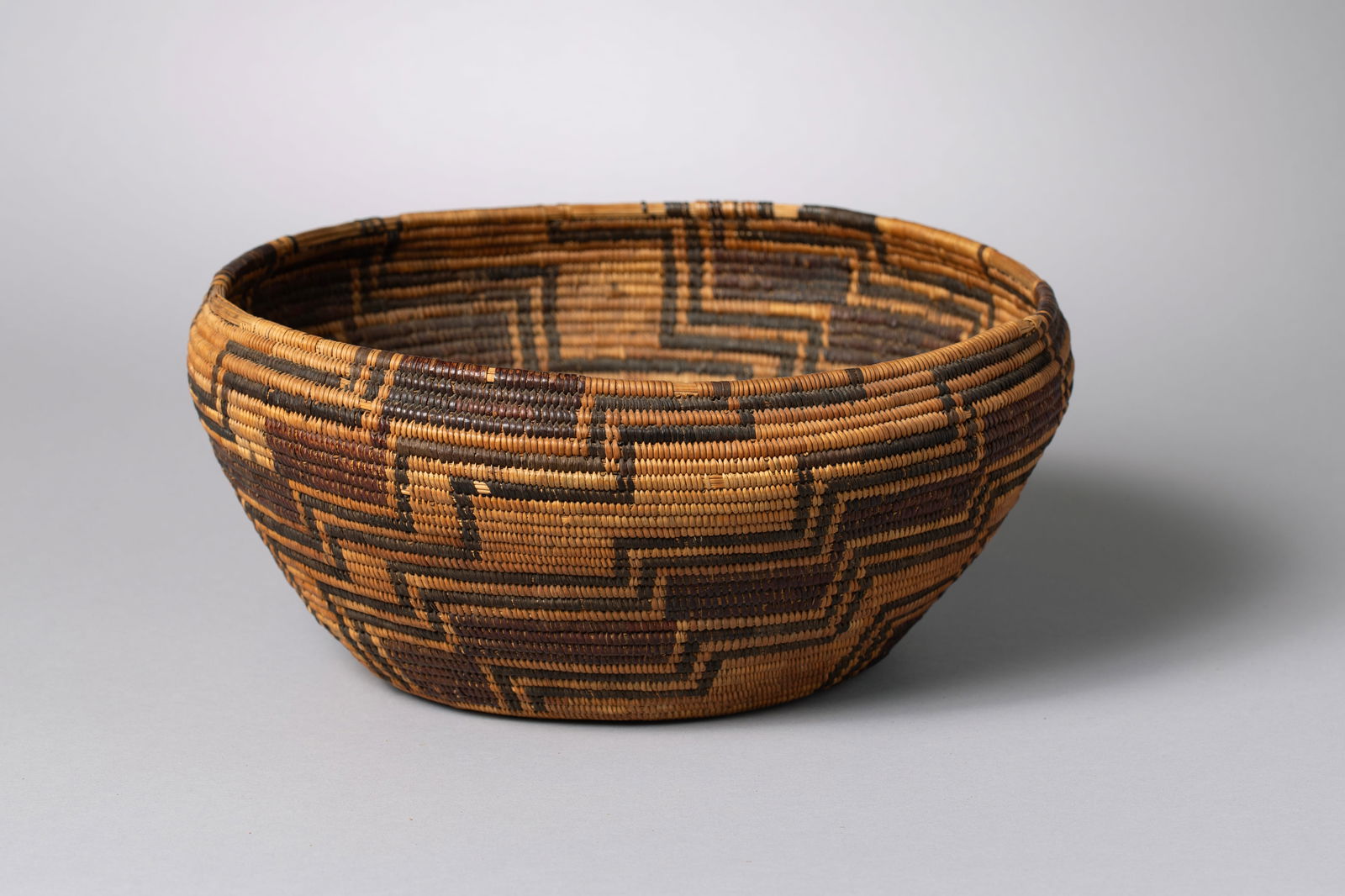 Tri-Color Coiled Pima Basket Bowl: Featuring curved walls decorated in willow, devil's claw, and reddish yucca-root dye and a continuous stepped maze pattern11" Diameter, 5" Height, 9.5" Opening, 6" Bottom