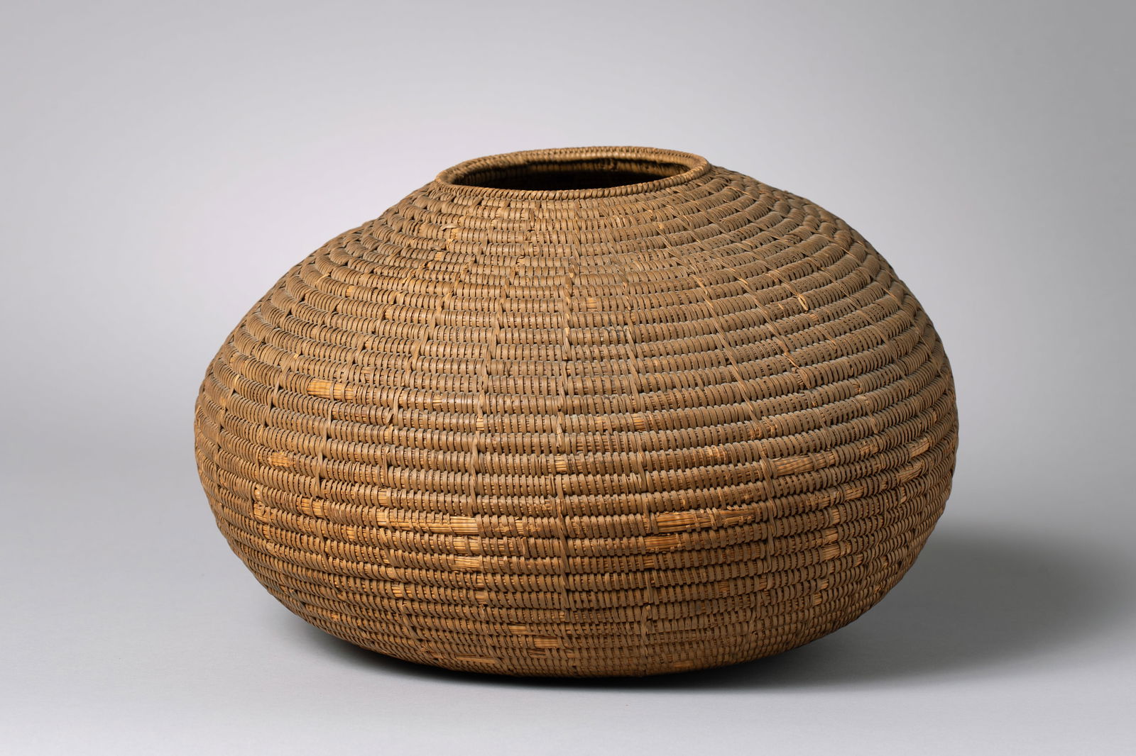 Southwest Native American Woven Olla Basket: Hand-coiled of undyed willow splints, the body swelling to a full, globular form before tapering to a small, upright mouth9.5" height, 13" diameter, 4.5" openingCa. late 19th to early 20th century