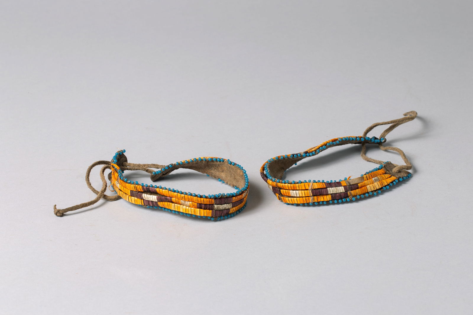 Early Northern Plains Porcupine quill Arm Bands: Each band has 3 rows of multicolor wrapped quill strips attached to hide with blue glass beads outlining the edge. 12"L, 3/4"W