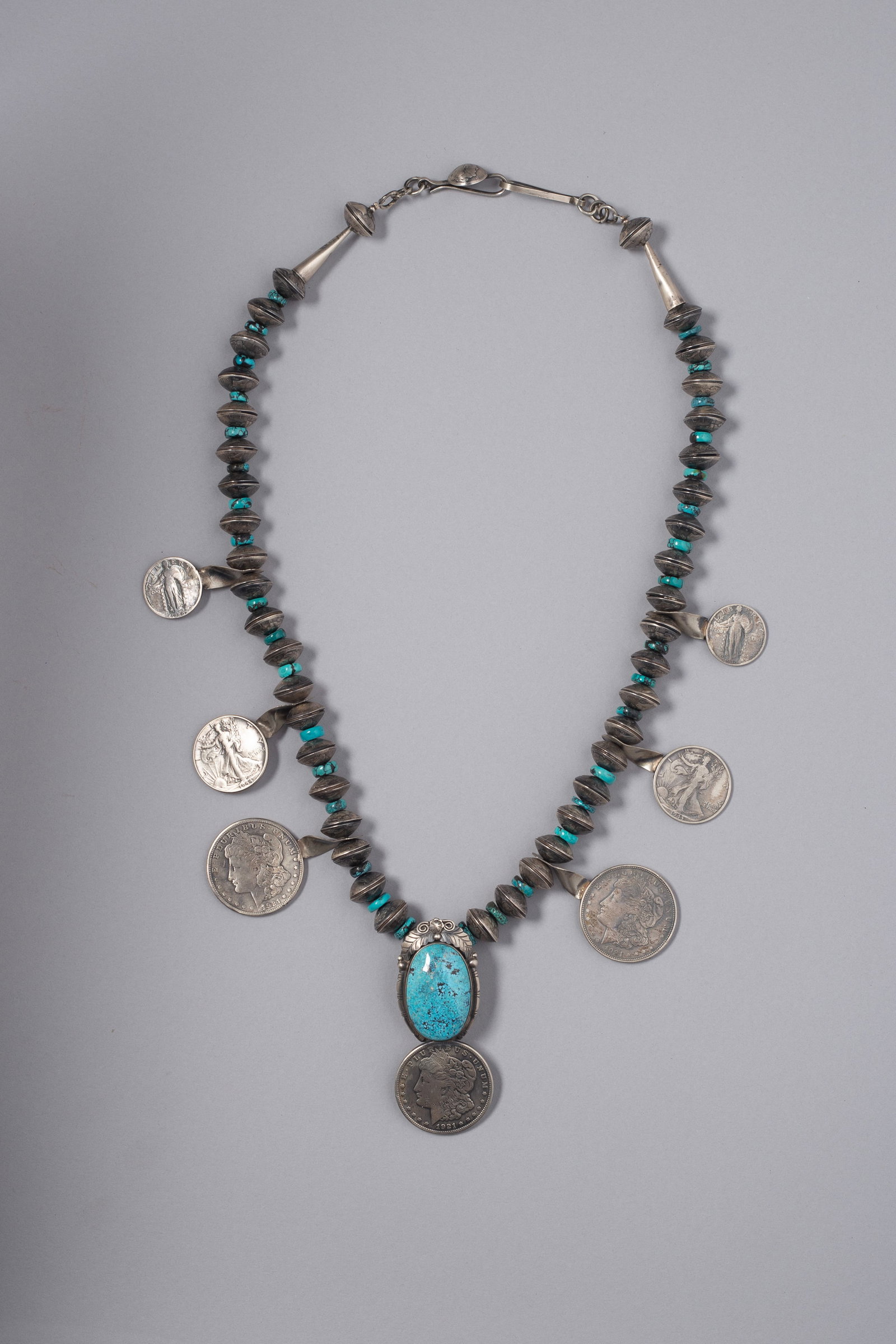 Navajo Coin & Turquoise Squash Blossom: Silver coin squash blossom necklace by Betta Lee, consisting of Early 20th Century Morgan Silver Dollars, Walking Liberty Half-Dollars, Standing Liberty Quarters and silver beads made of mercury dimes