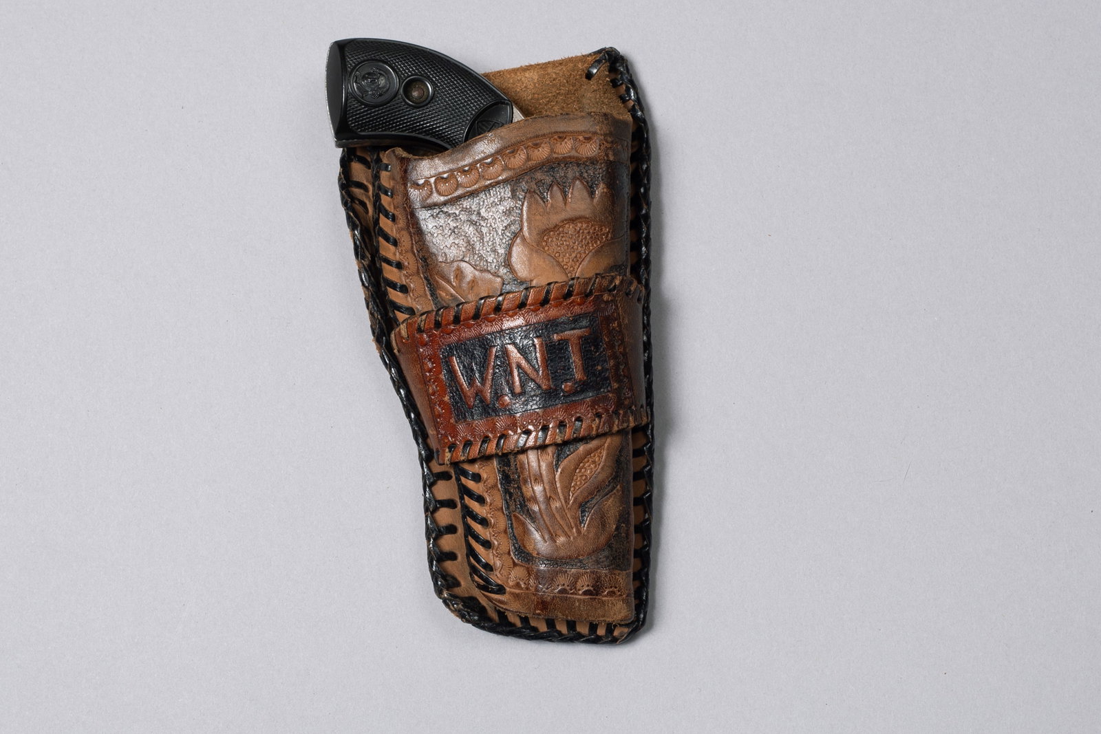 Antique Liberty Revolver with Tooled Holster: "Hideout" gun marked "Liberty" on top of barrel, nickel finish with black rubber grips which have the American shield and George Washington image on them, spur trigger, .22 caliber rimfire, with flora